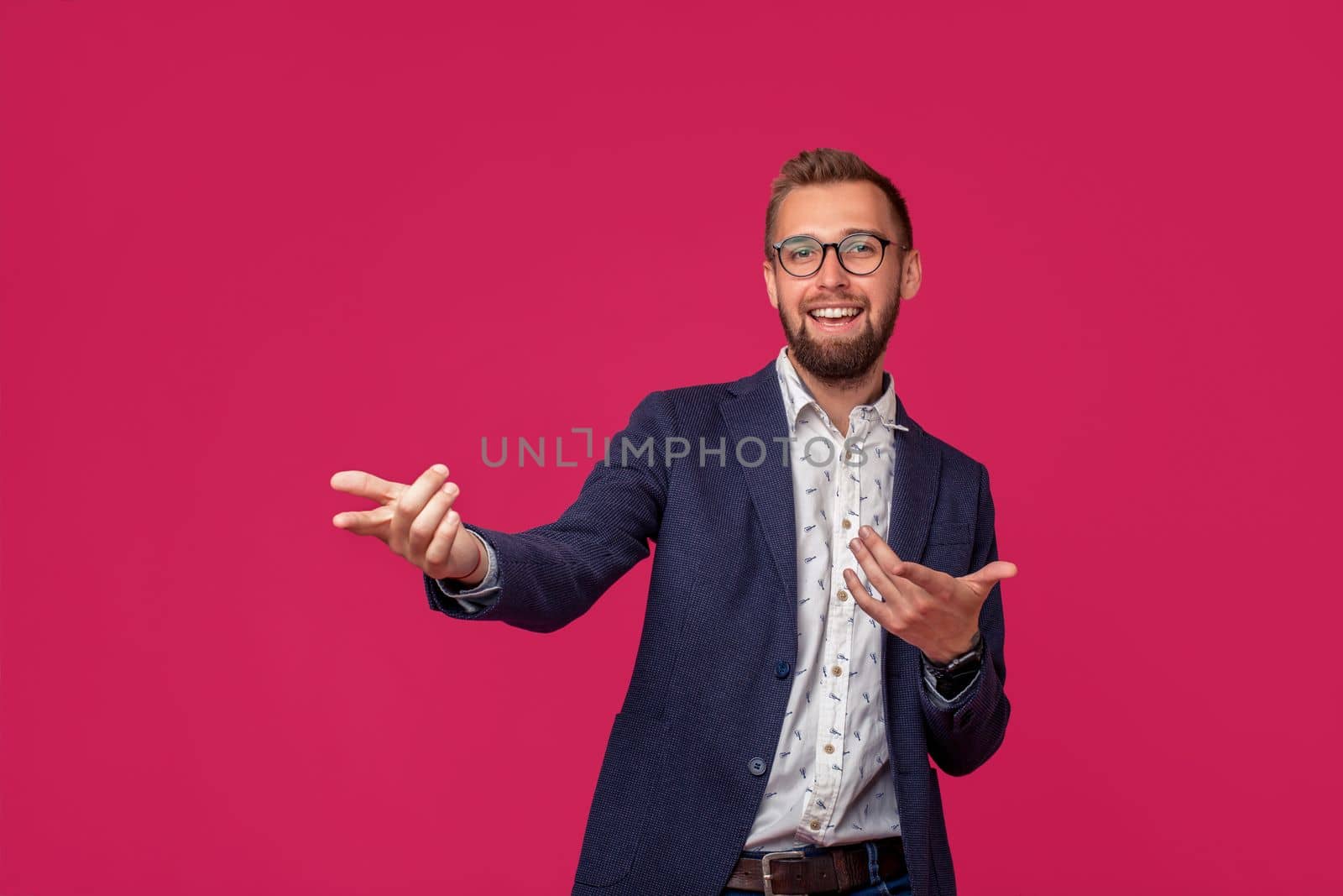 Studio shot of attractive brunette business man with glasses, in casual shirt, stylish black jacket talking, smiling. Isolated pink background.