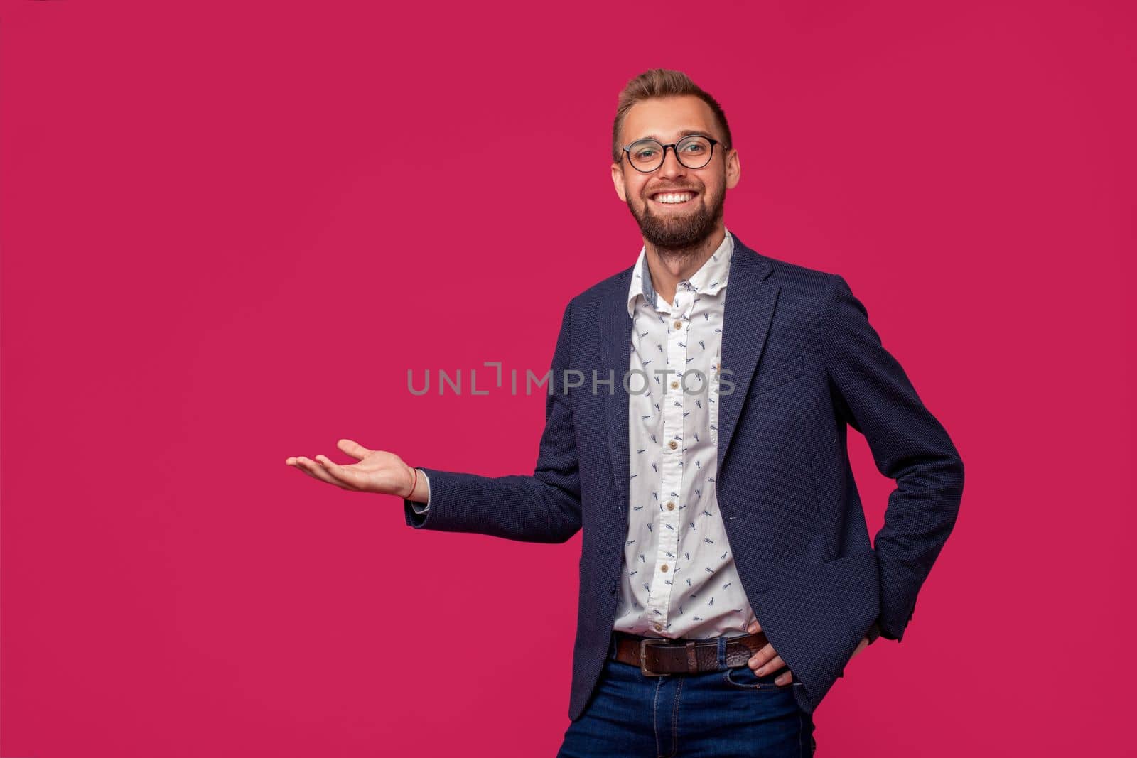 Studio shot of attractive brunette business man with glasses, in casual shirt, stylish black jacket talking, smiling. Isolated pink background.