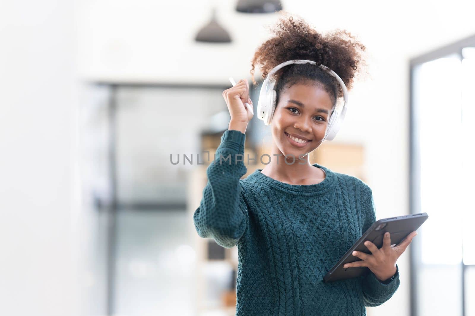 Portrait of smiling young black woman listening music with headset and digital tablet..