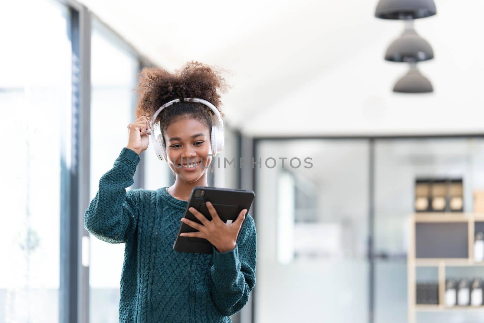 Portrait of smiling young black woman listening music with headset and digital tablet..