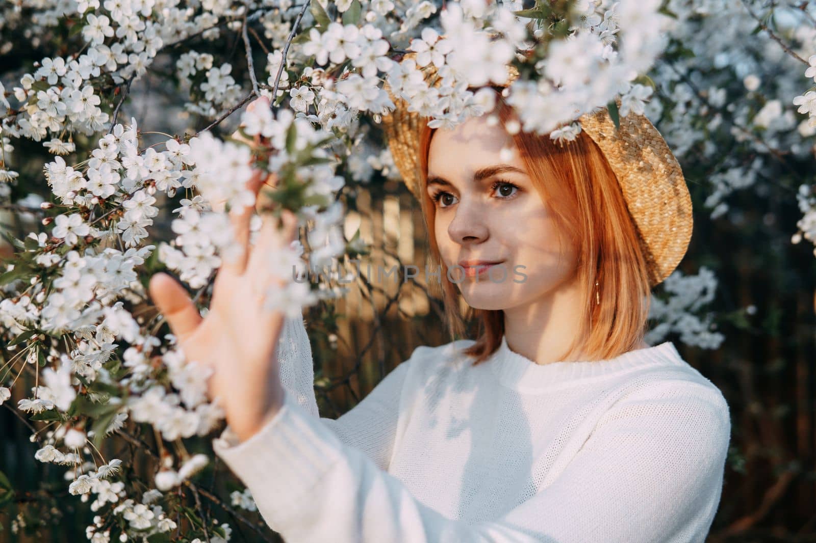 Portrait of a woman in a straw hat in a cherry blossom. Free outdoor recreation, spring blooming garden.