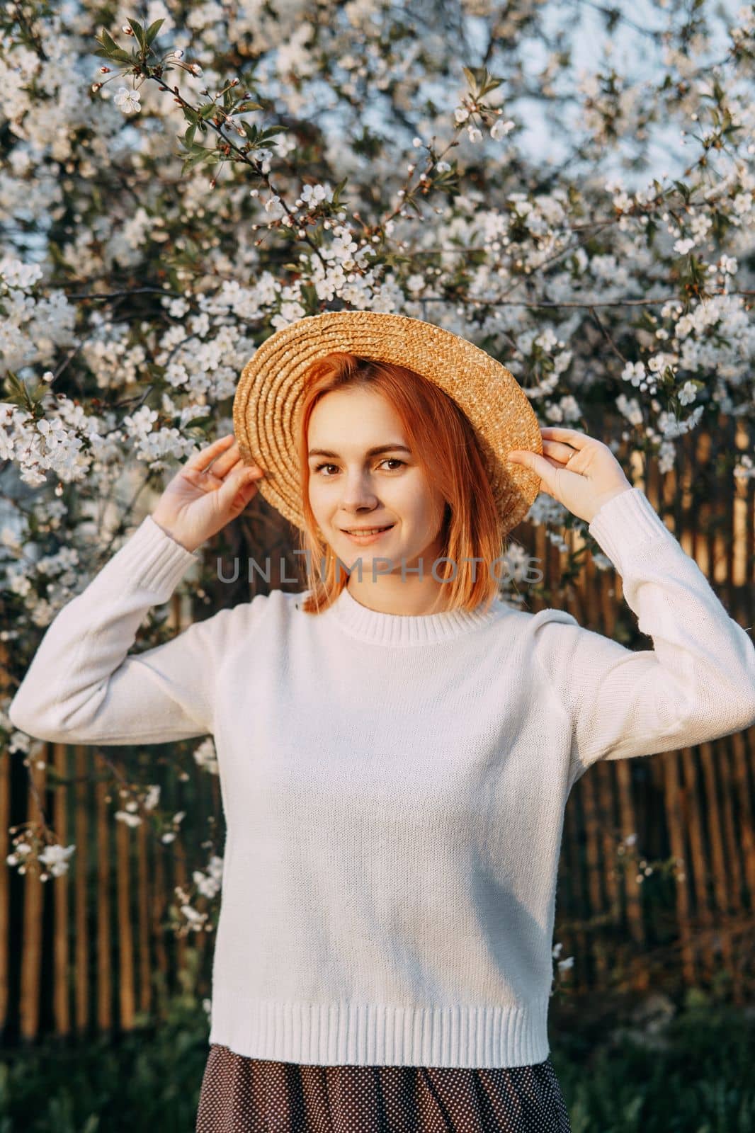 Portrait of a woman in a straw hat in a cherry blossom. Free outdoor recreation, spring blooming garden.