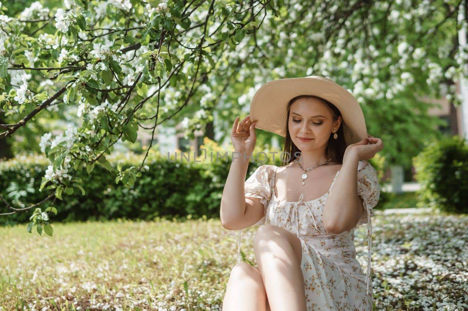 An attractive long-haired woman walks in the spring in the park of blooming apple trees. Spring portrait of a woman
