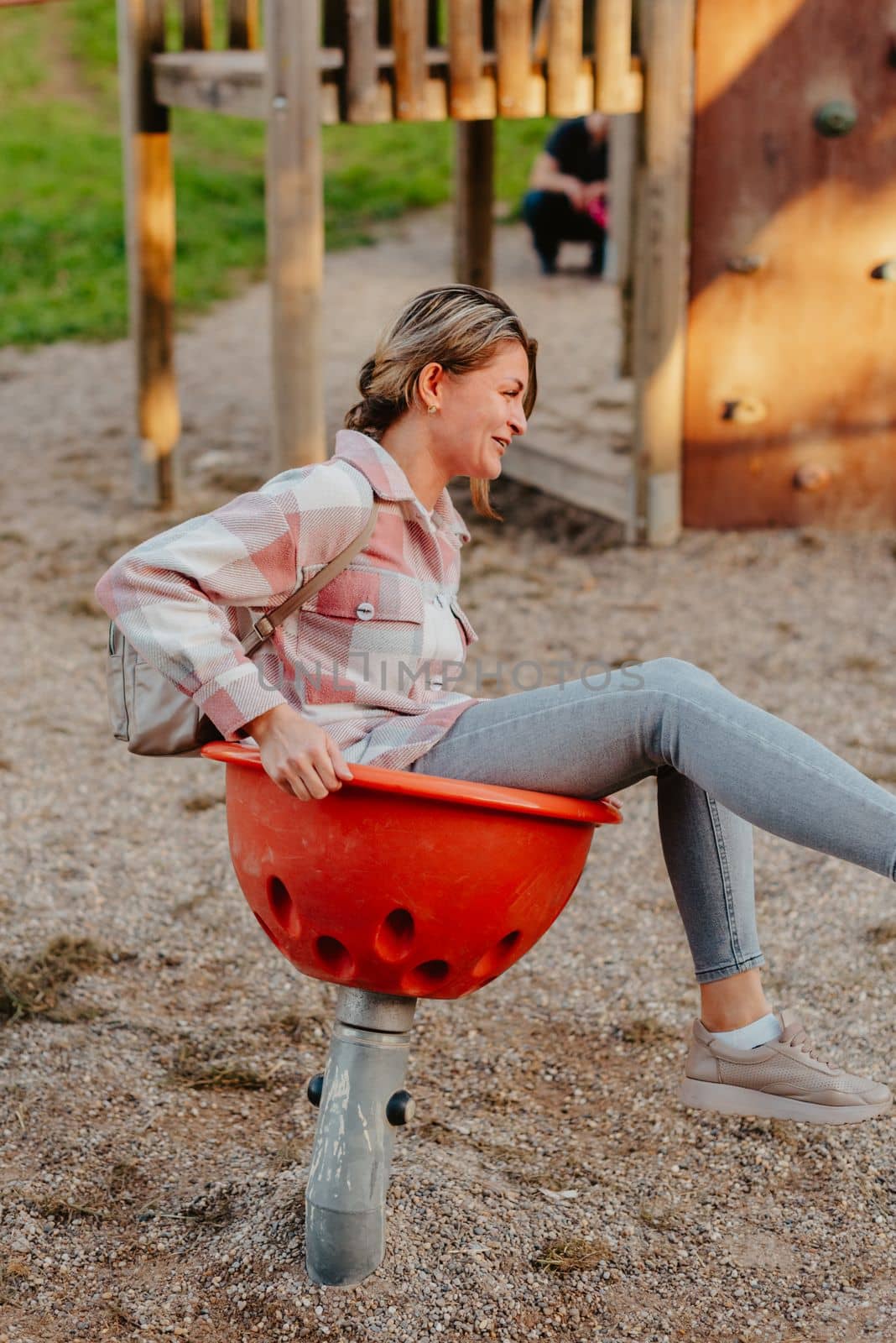 Woman having fun on a swing. Motherhood and childhood concept. Sunny summer day. Beautiful girl is having fun outside. A woman swings on a swing in the park. by Andrii_Ko