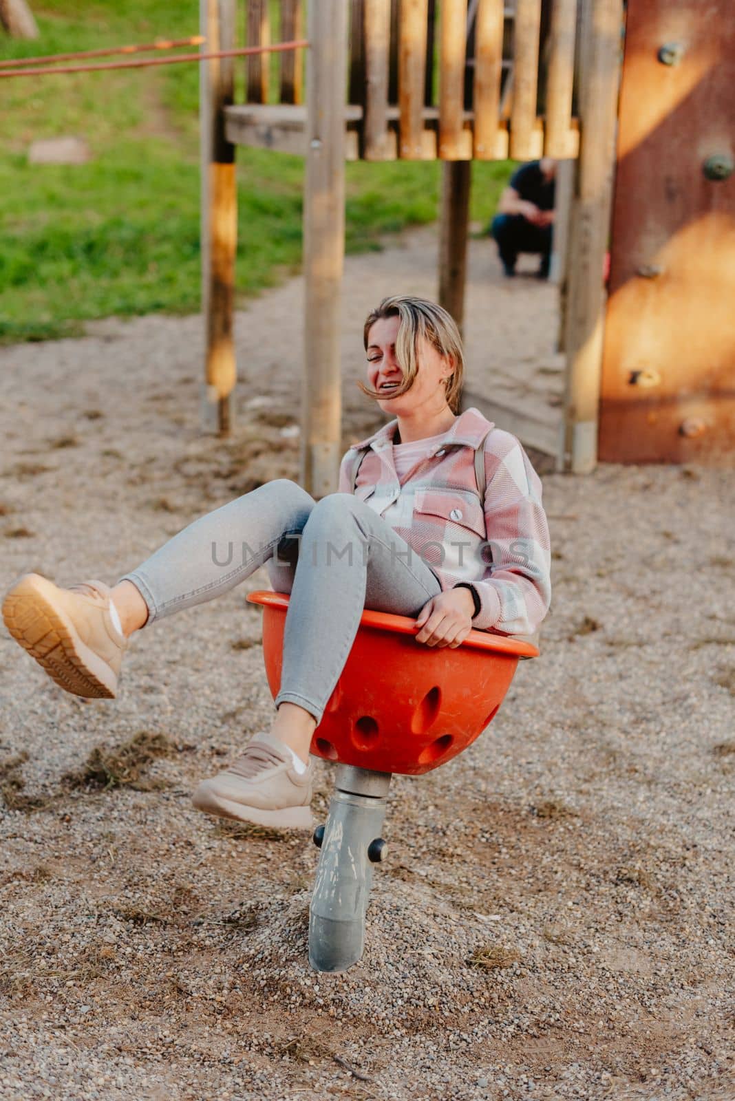 Woman having fun on a swing. Motherhood and childhood concept. Sunny summer day. Beautiful girl is having fun outside. A woman swings on a swing in the park. by Andrii_Ko