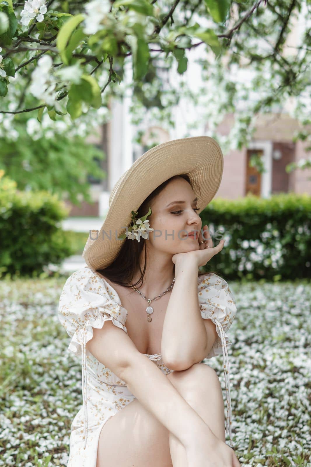 An attractive long-haired woman walks in the spring in the park of blooming apple trees. Spring portrait of a woman