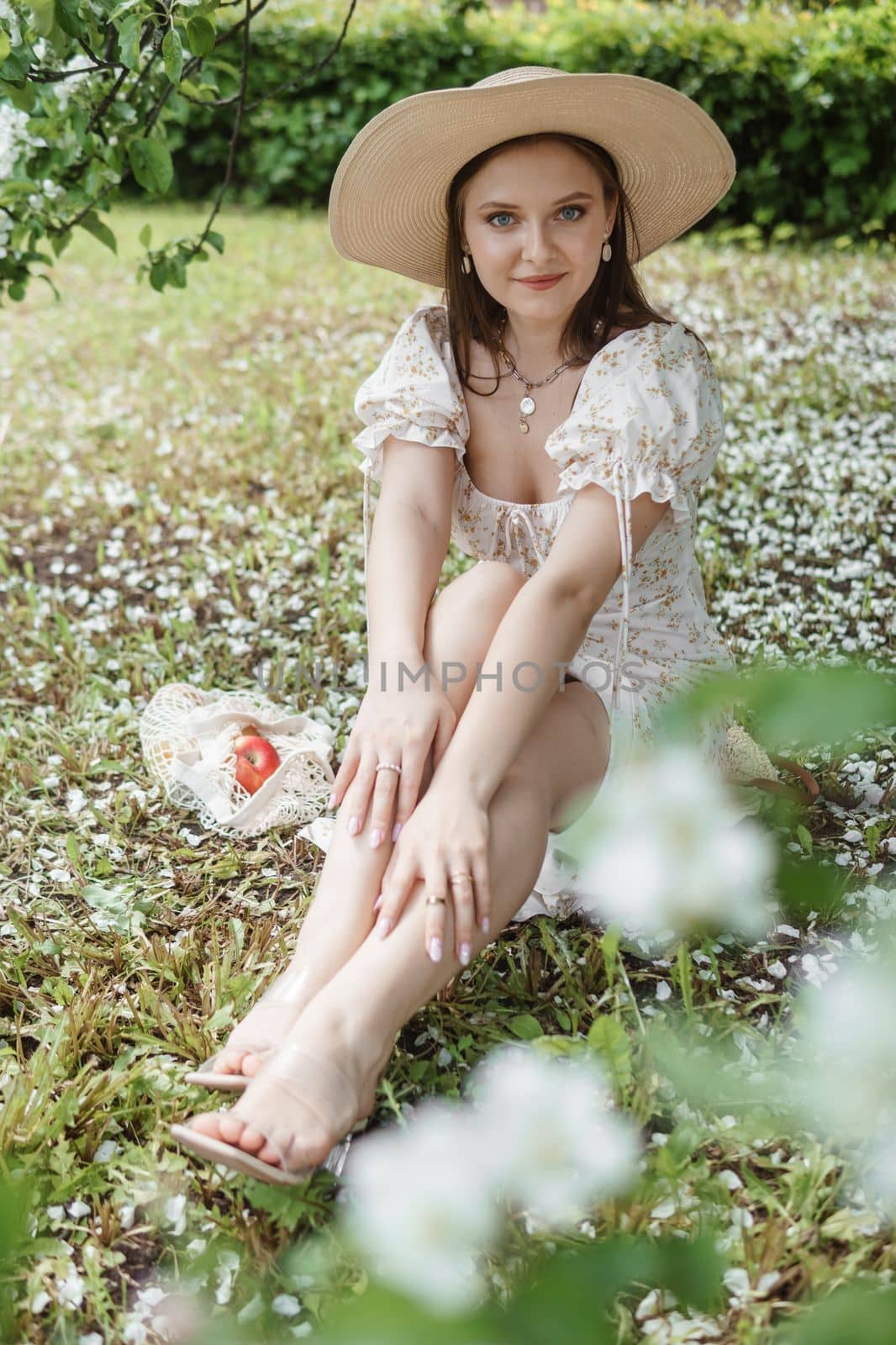 An attractive long-haired woman walks in the spring in the park of blooming apple trees. Spring portrait of a woman