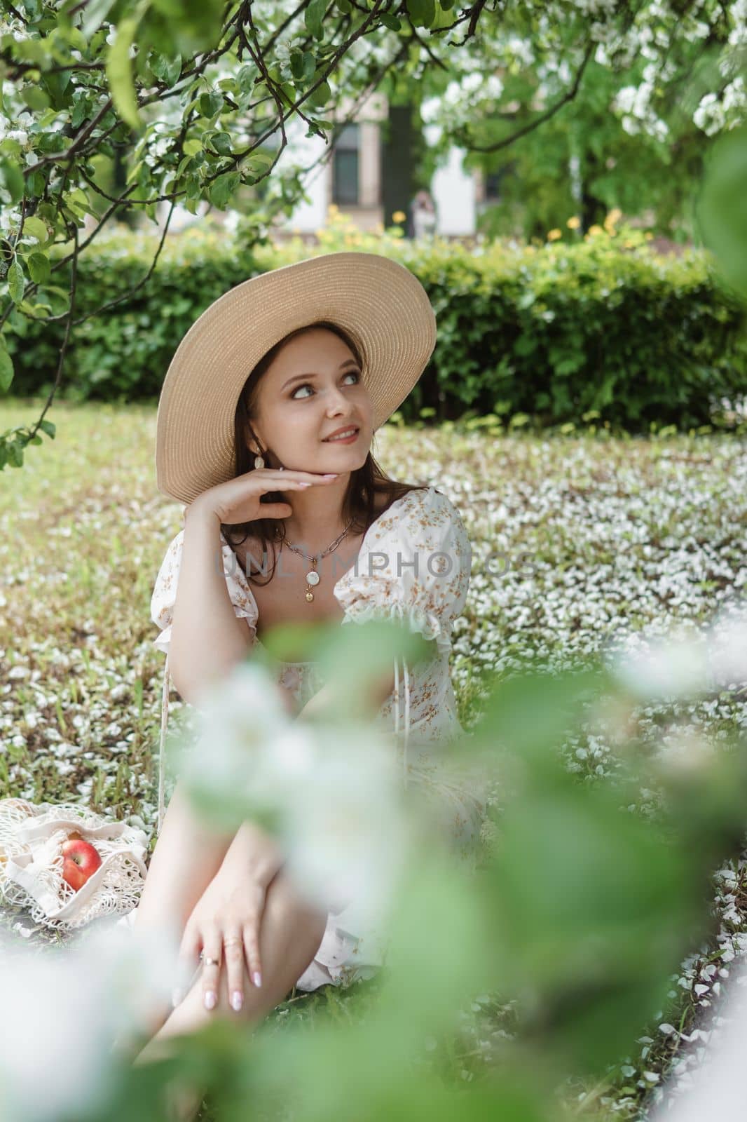 An attractive long-haired woman walks in the spring in the park of blooming apple trees. Spring portrait of a woman
