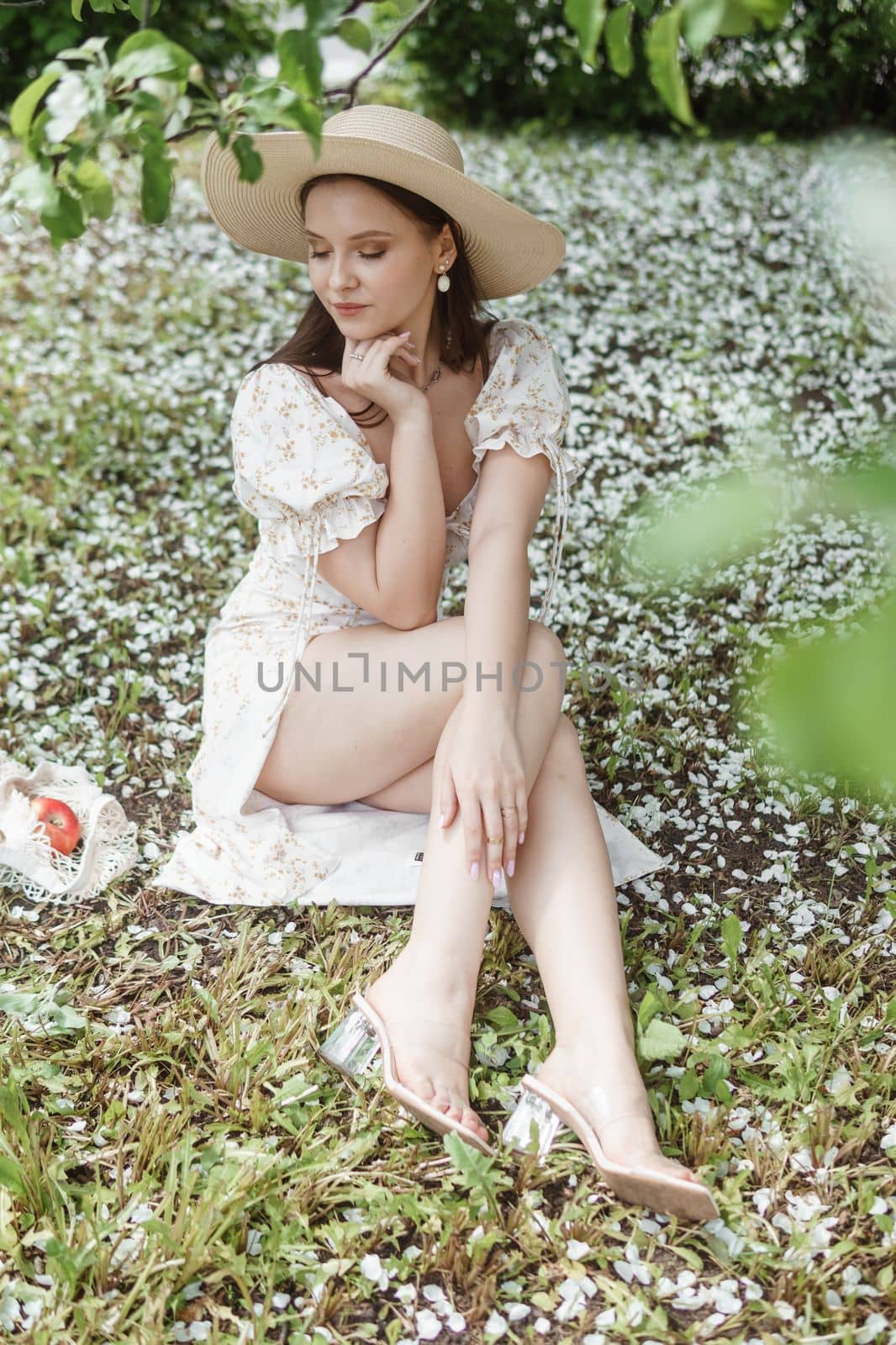 An attractive long-haired woman walks in the spring in the park of blooming apple trees. Spring portrait of a woman