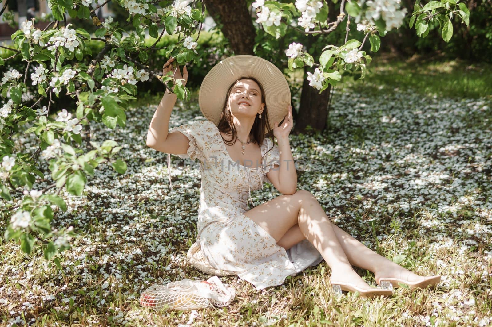 An attractive long-haired woman walks in the spring in the park of blooming apple trees. Spring portrait of a woman