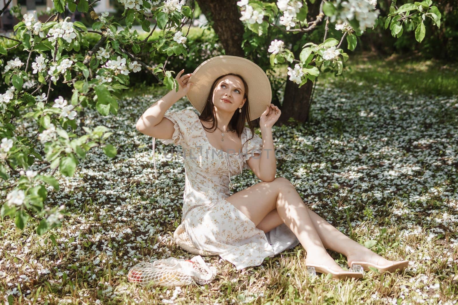 An attractive long-haired woman walks in the spring in the park of blooming apple trees. Spring portrait of a woman