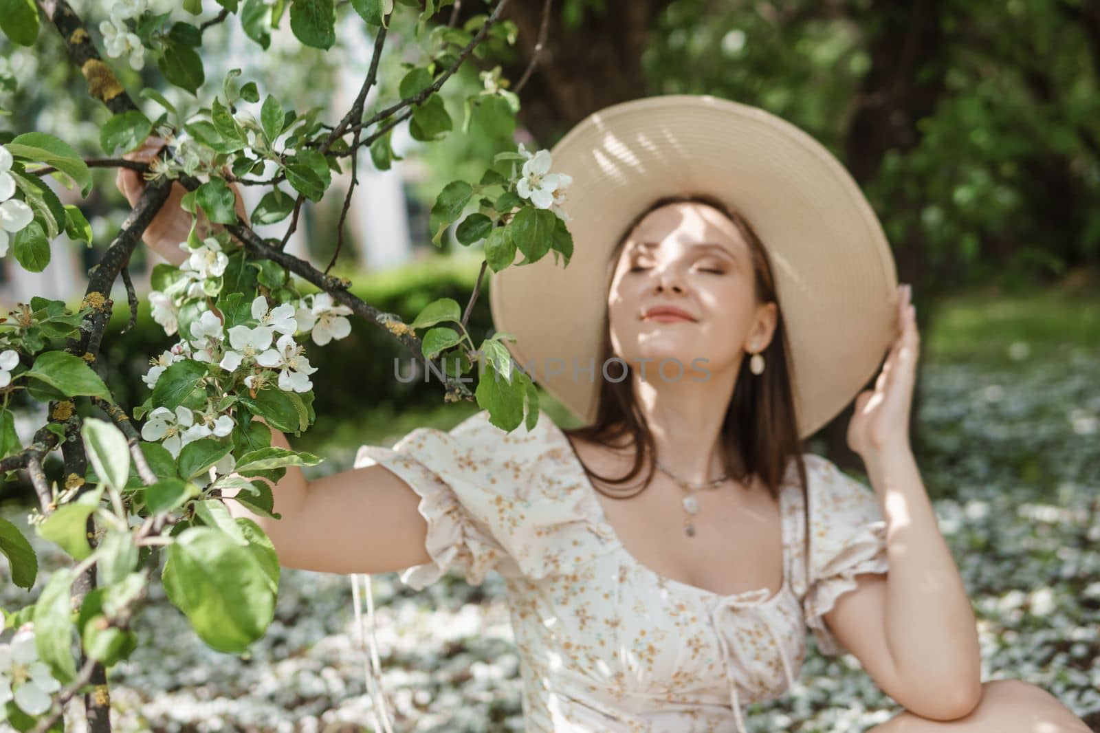 An attractive long-haired woman walks in the spring in the park of blooming apple trees. Spring portrait of a woman