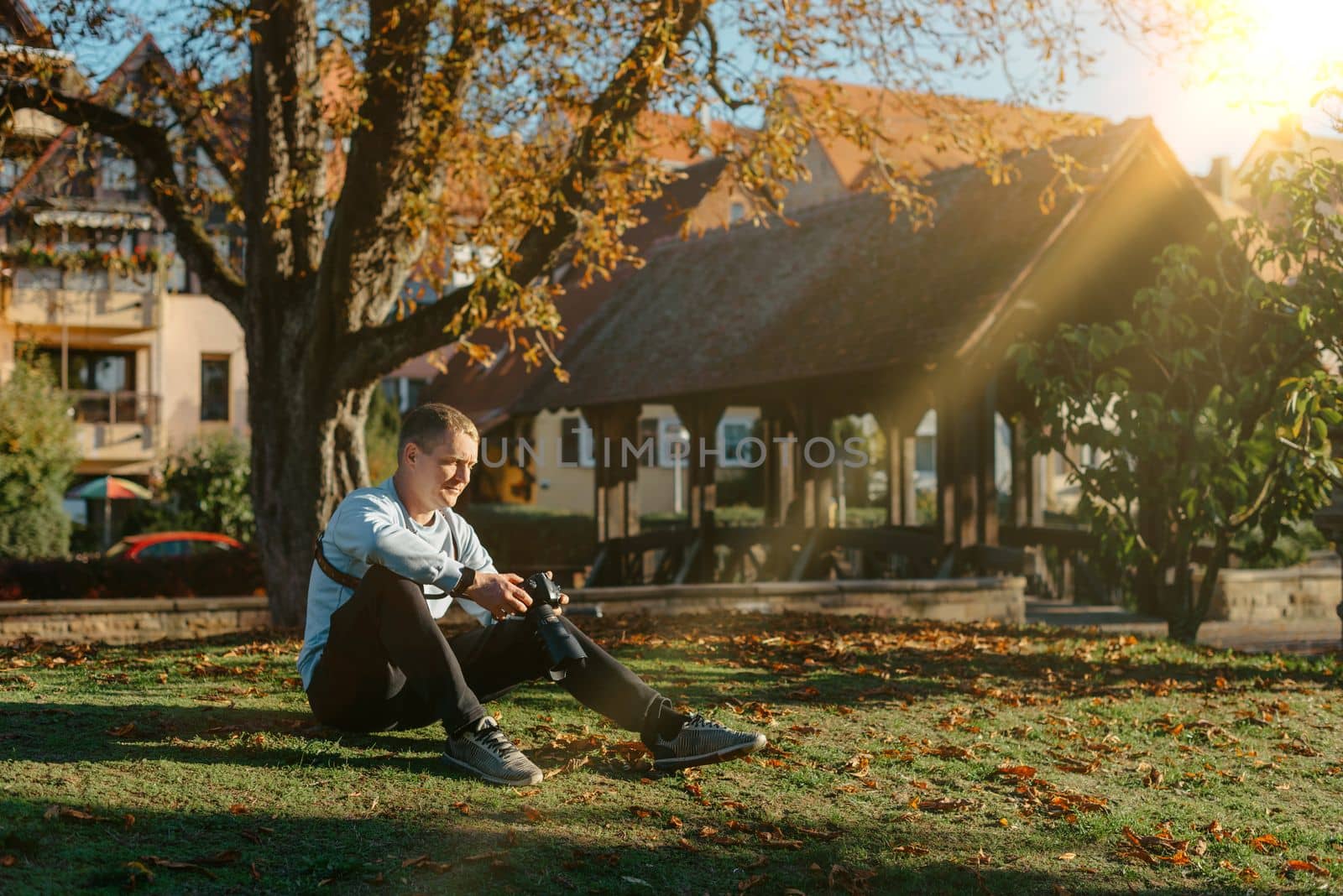 Professional photographer taking picture of beautiful autumn park. man professional photographer sit with camera in autumn park