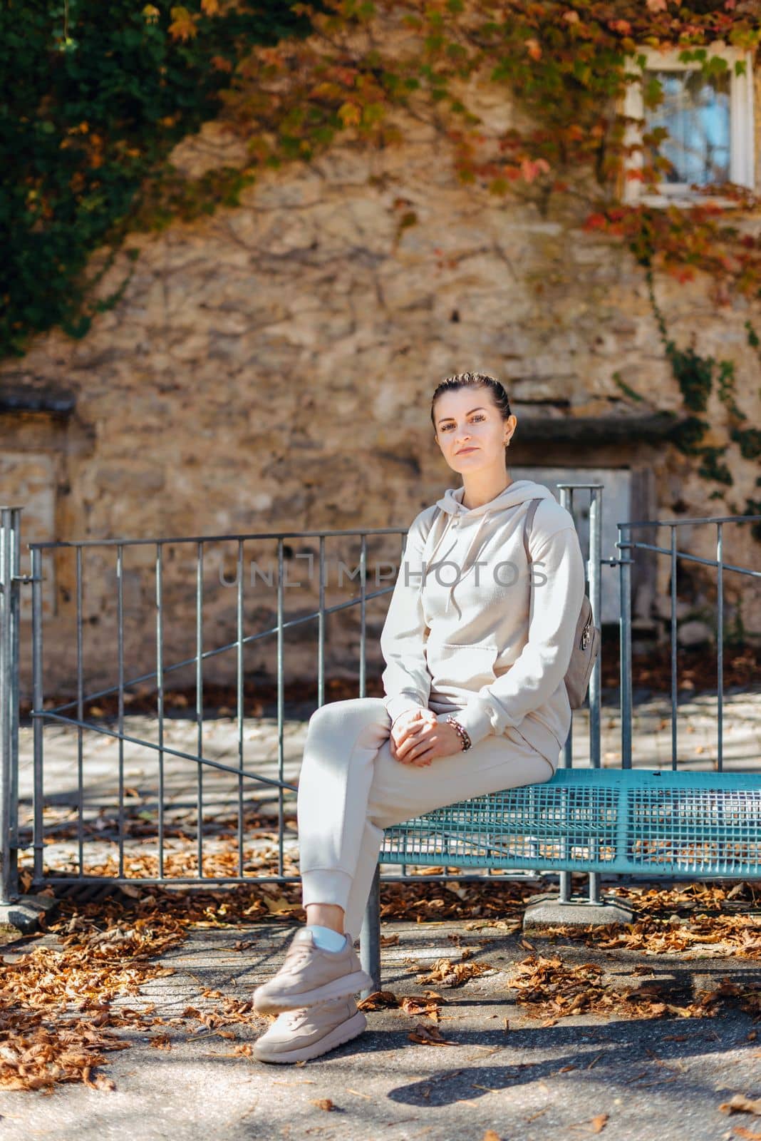 Attractive young woman sitting on a bench enjoying a view of medieval town in Europe. Summer holidays concept.