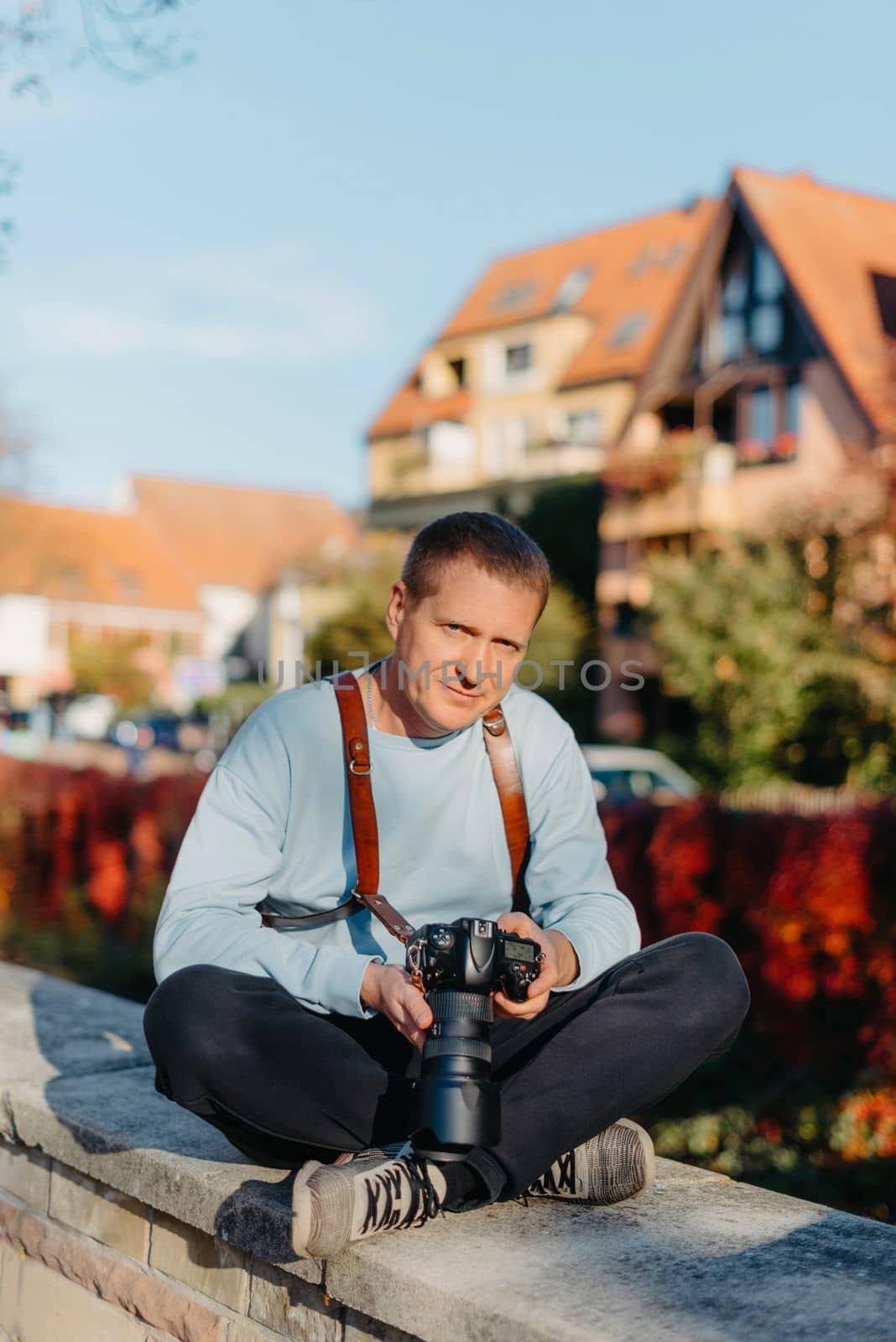 Man Sitting on Stairs in Old European City And Holding Photo Camera. Contemporary Stylish Blogger And Photographer