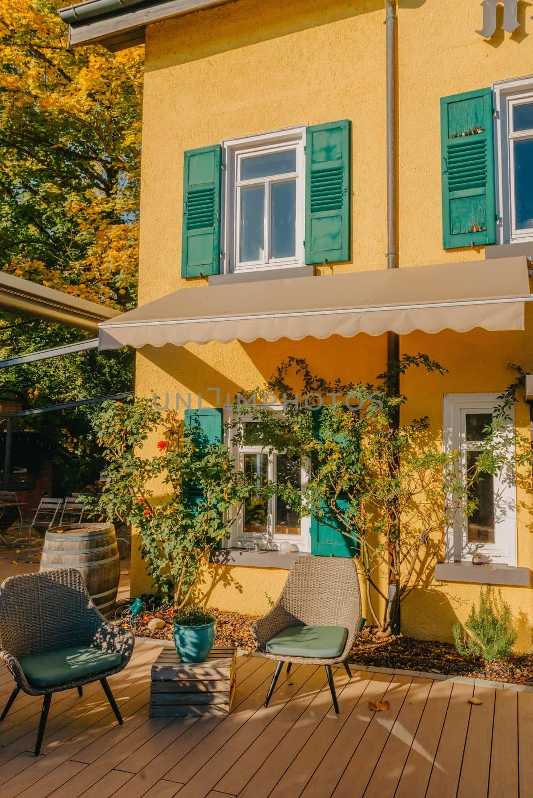 Image of a empty coffee tables arranged in backyard of a house. Autumn in Germany, Europe. Outdoor table in street cafe. autumn outdoor cafe wooden furniture old europe. Autumn photo of old-fashioned cozy and empty outdoor cafe with wooden furniture in a European town. Cafe concept by Andrii_Ko