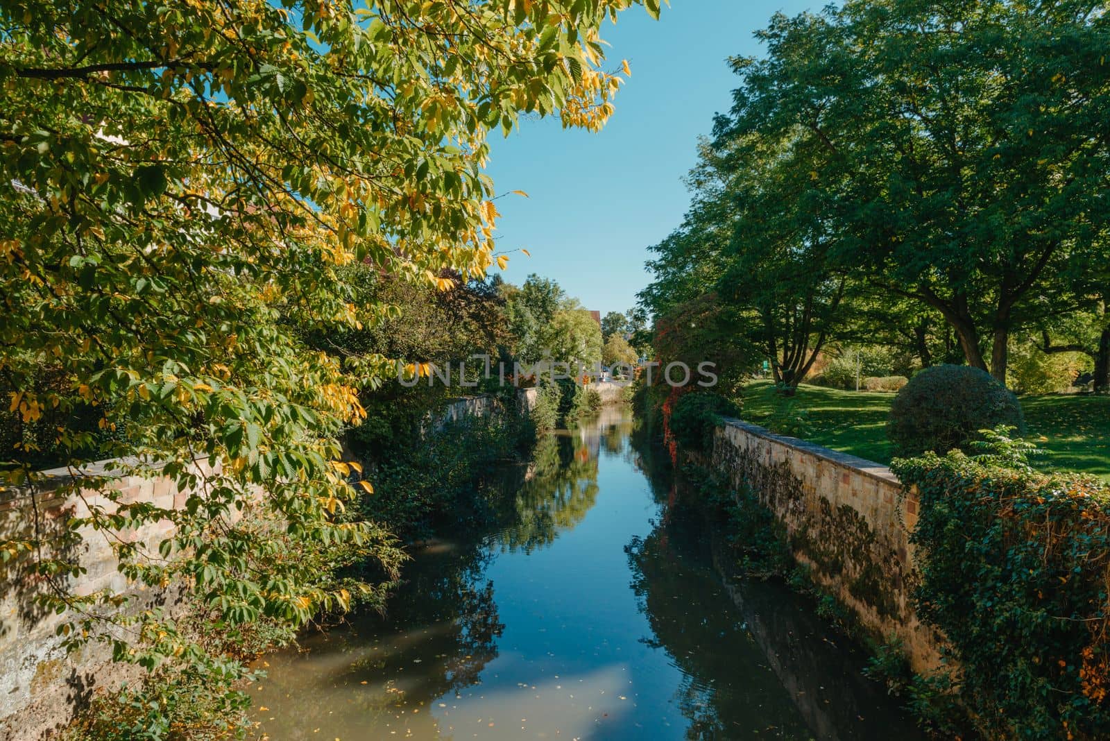 A wooden bridge in the park with and autumn colors of Bietigheim-Bissingen, Germany. Europe. Autumn landscape in nature. Autumn colors in the forest. autumn view with wooden bridge over stream in the park in autumn season