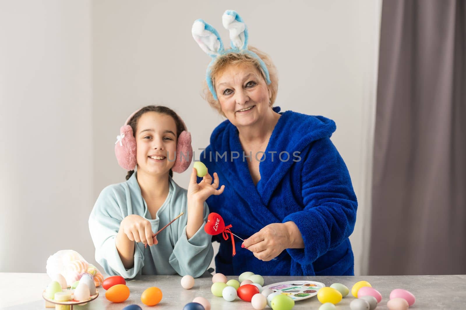 Little girl with grandmother dyeing Easter eggs.