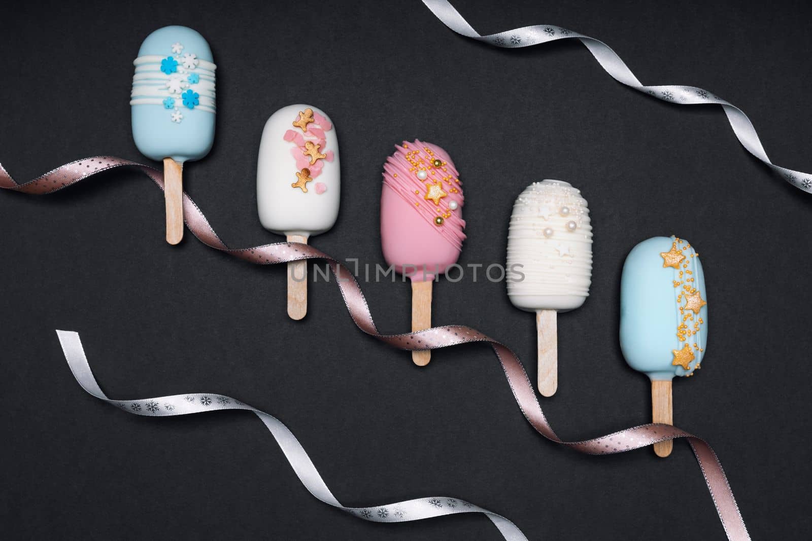 Cake pops ice creams with ribbons on black background. Top view.
