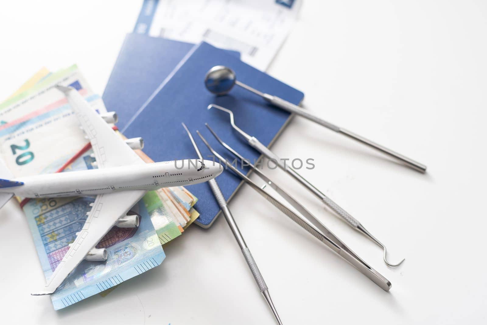 An Overhead View Of Dental Tools On Euro Notes, passport toy, airplane.