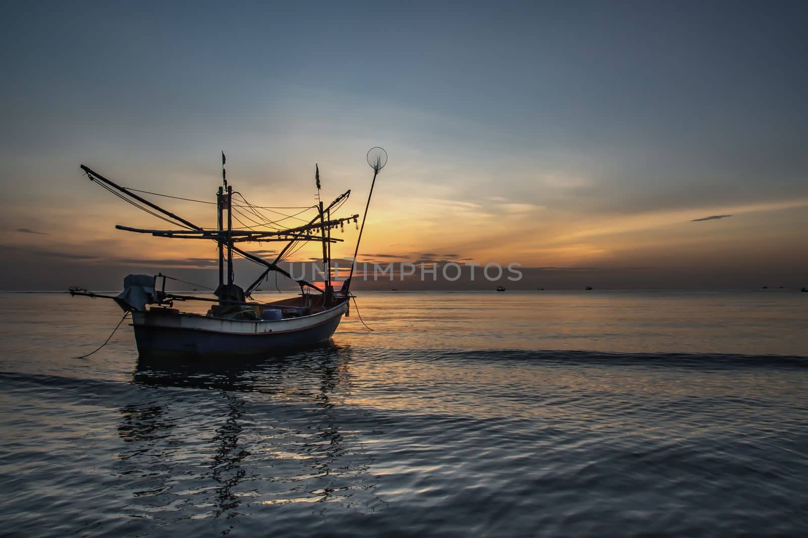 Thai fishing boat used as a vehicle for finding fish in the during beautiful twilight in the sea. No focus, specifically.