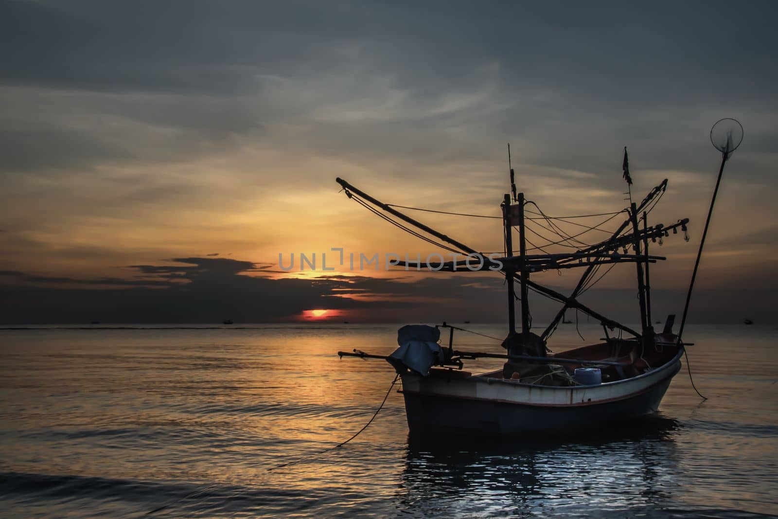 Thai fishing boat used as a vehicle for finding fish in the during beautiful twilight in the sea. No focus, specifically.