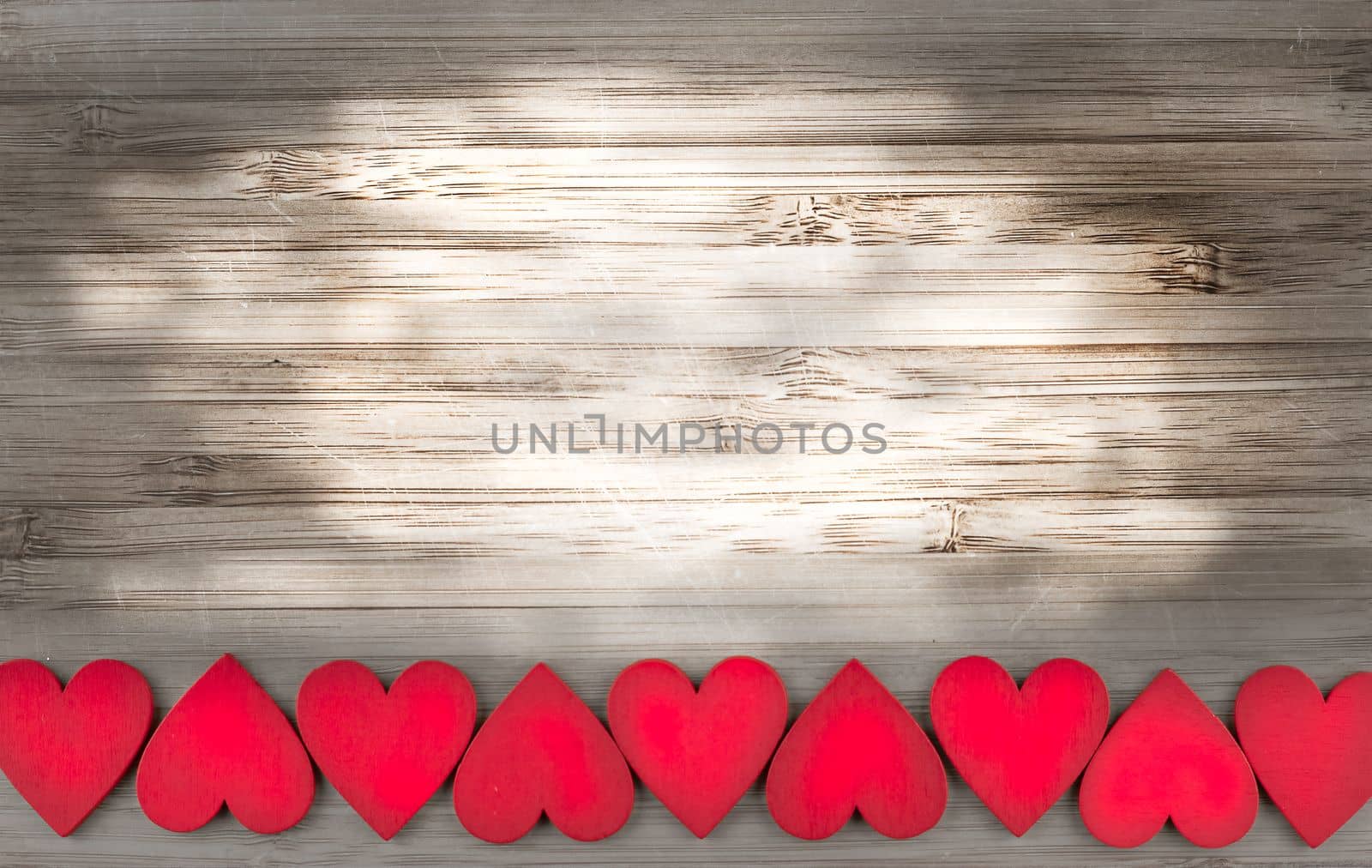 row of red wooden hearts at the bottom of wooden background