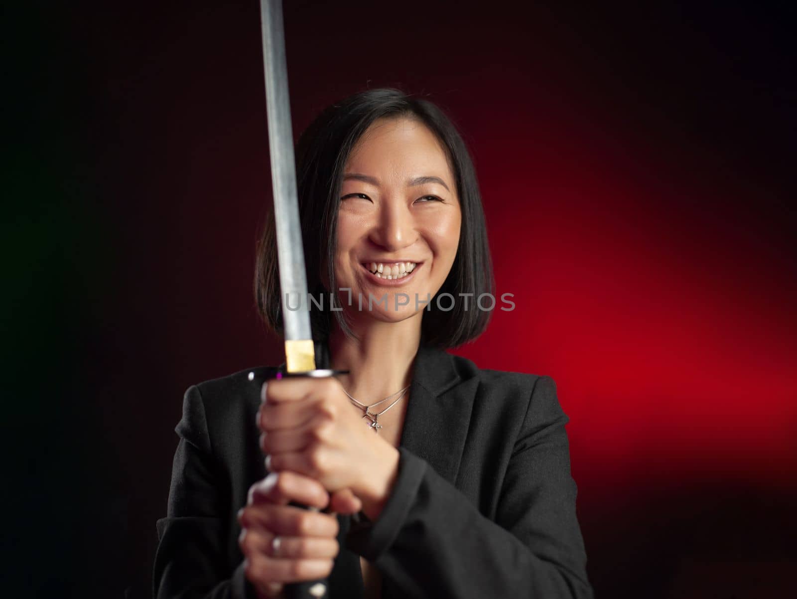 portrait of an Asian girl with a katana in her hands posing emotionally on a black background copy paste