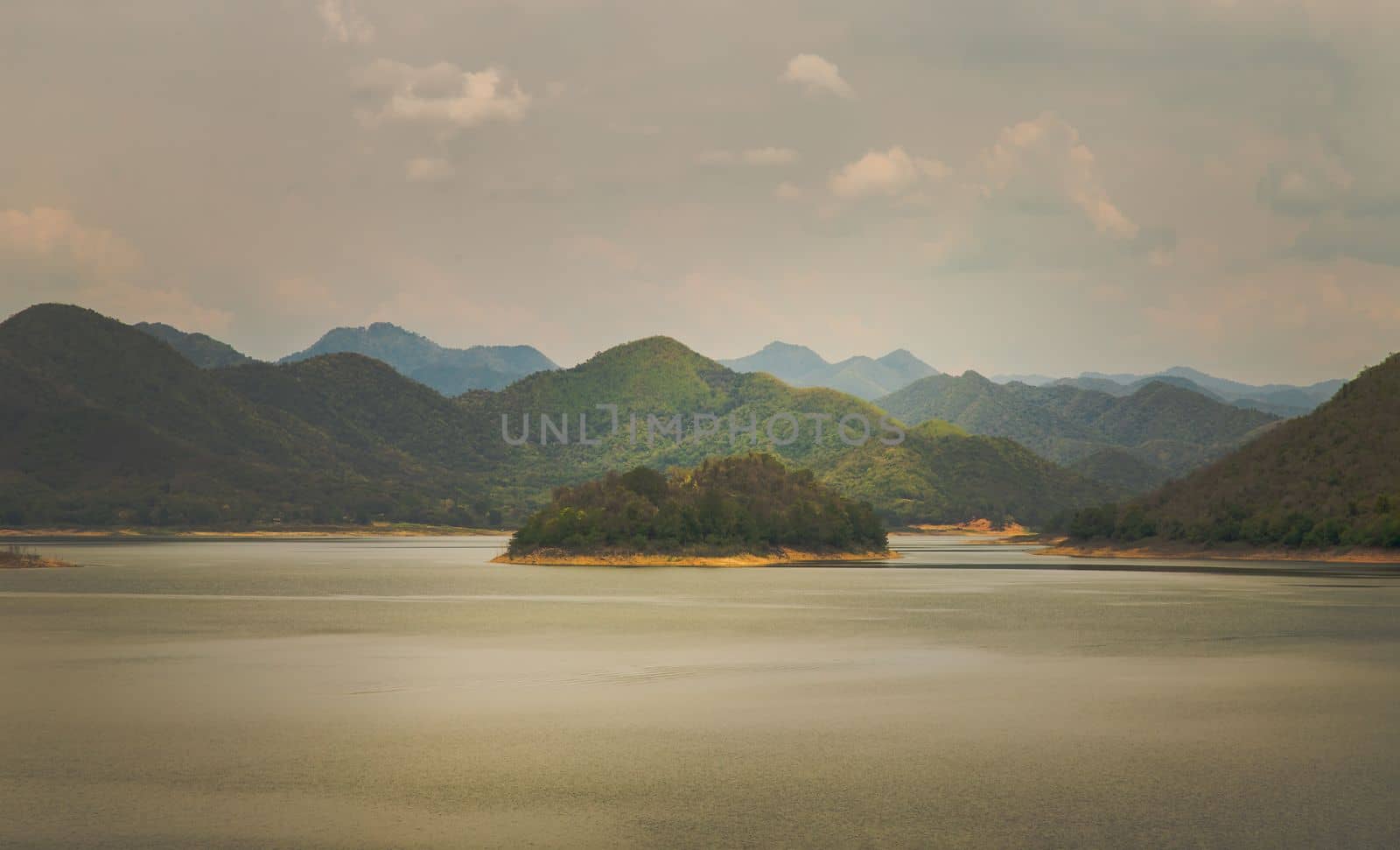 View of lake shore with mountains range in background at sunrise or sunset. No focus, specifically.