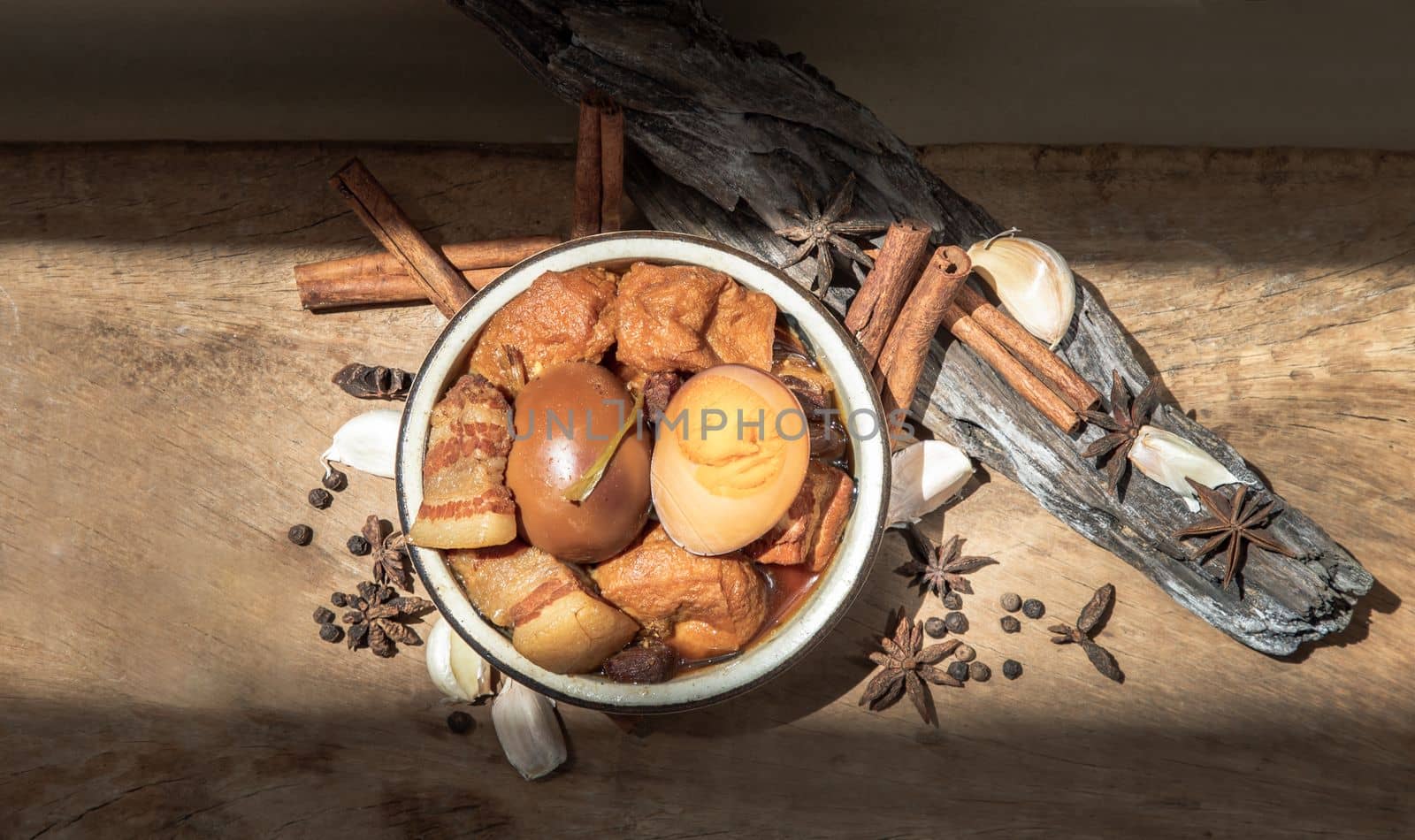 Boiled egg (kai pa lo) and Belly Pork Chinese Five-Spice Stewed with Tofu in brown sauce decorated with anise star, cinnamon, garlic and black pepper on old wooden table, Asia food, Copy space, Selective focus.