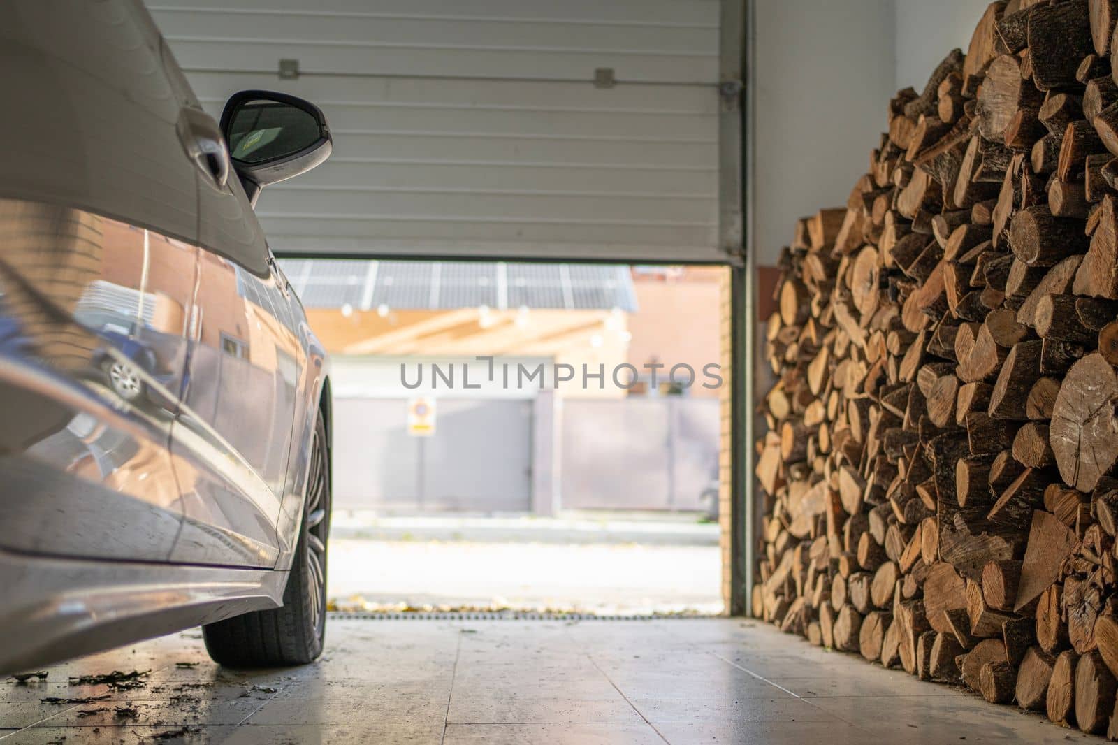 Low angle view of garage with a parked car full of firewood for the winter.