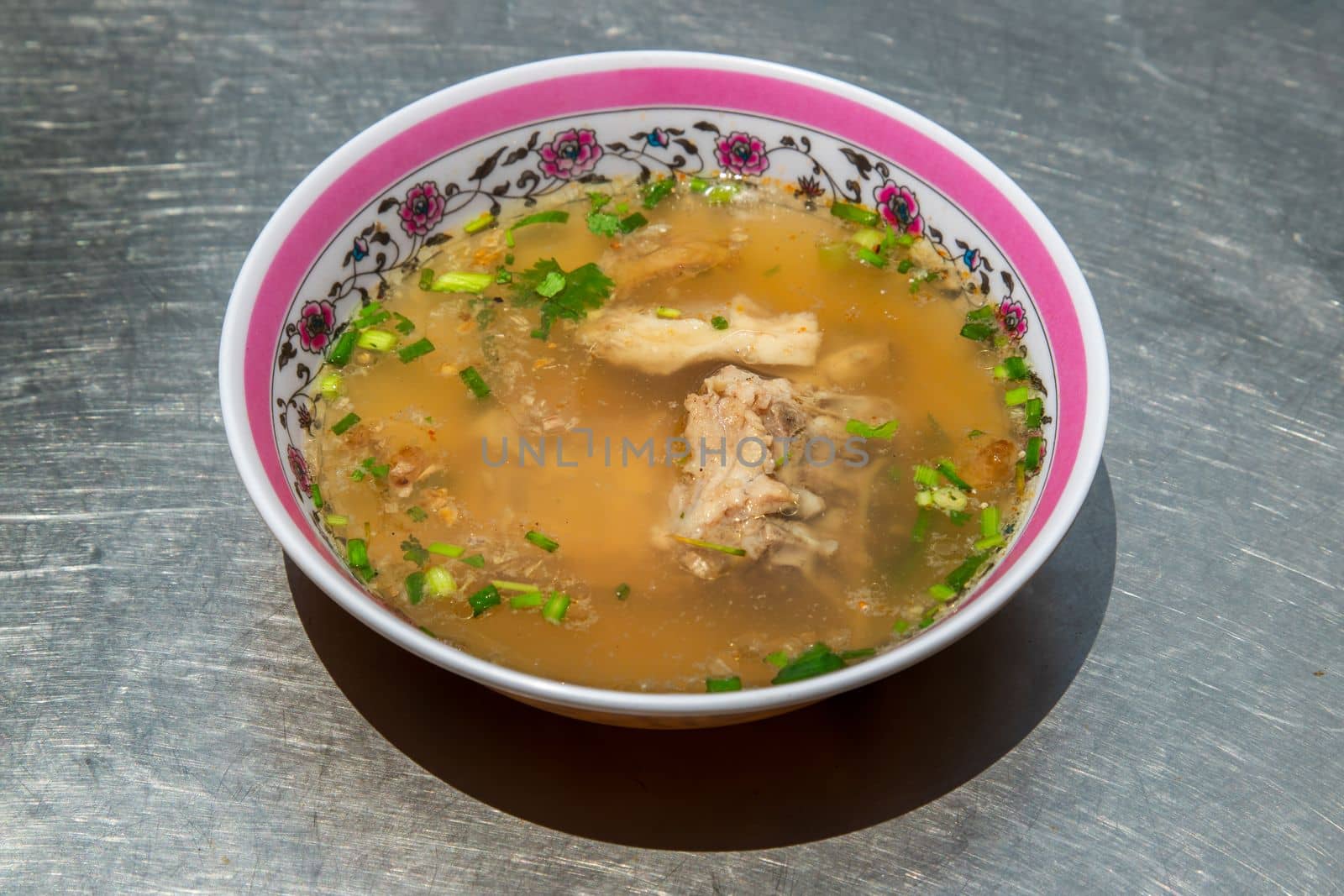 Hot clear soup of fresh pork rib seasoning with soy sauce and pepper. Pork bone soup in white bowl, Selective focus.
