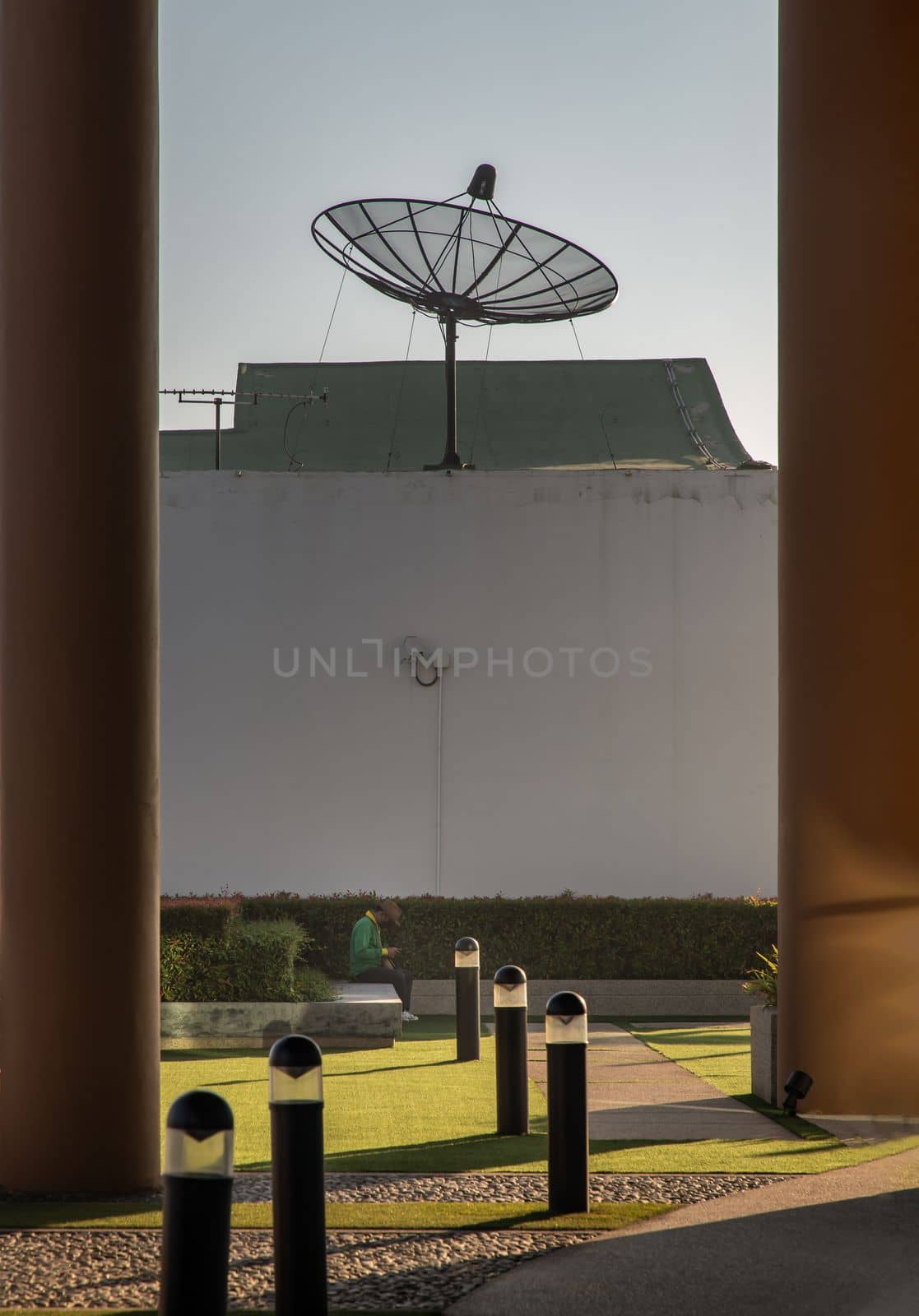 Bangkok, Thailand - Jan 10, 2022 : The gardener was using smartphone while sitting on stone bench on rooftop garden. No focus, specifically.