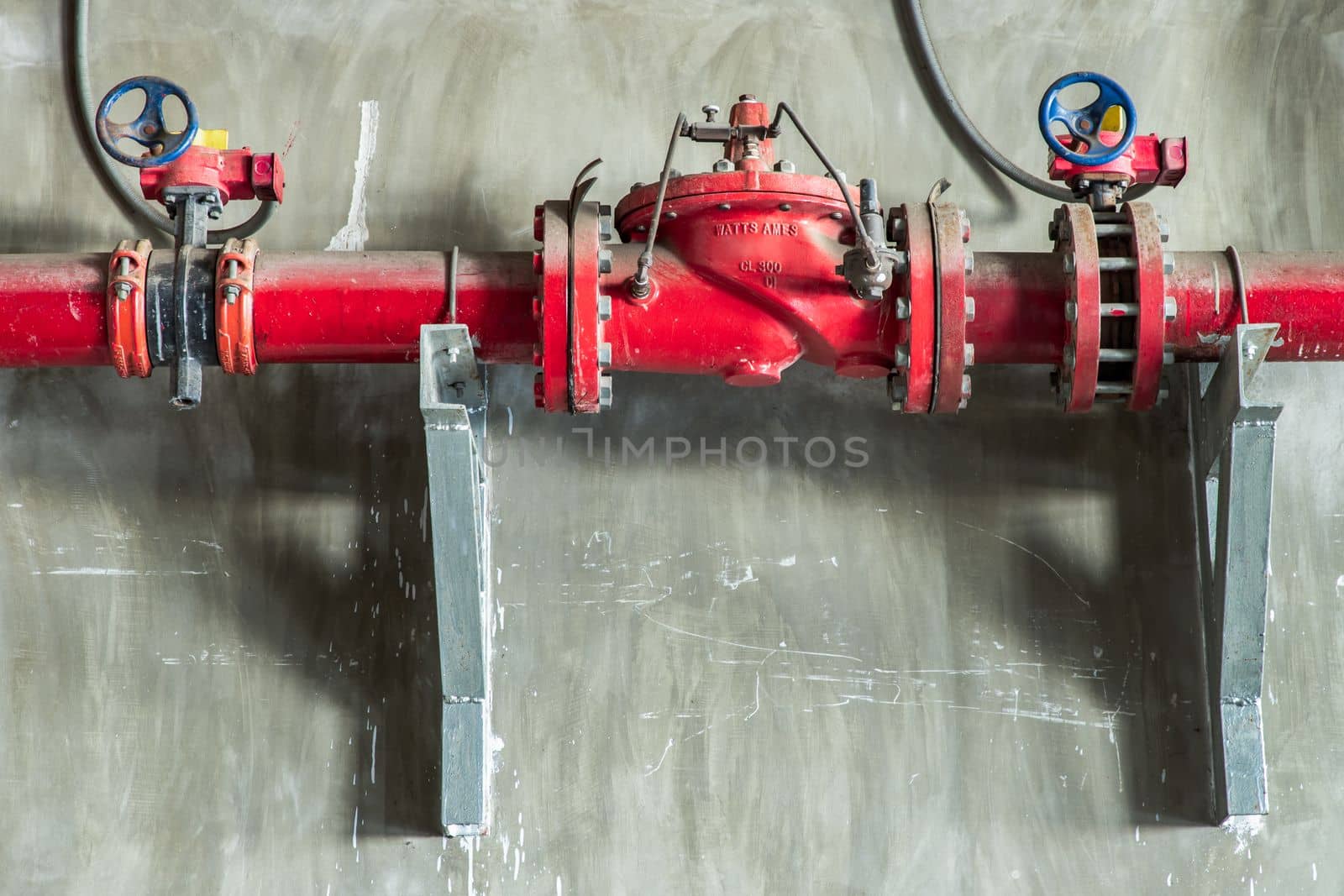 Red water or gas pipeline with gate pressure valve on concrete wall. Industrial tubes and valves, Line pipe industrial and extinguisher pump, Copy space, Selective focus.