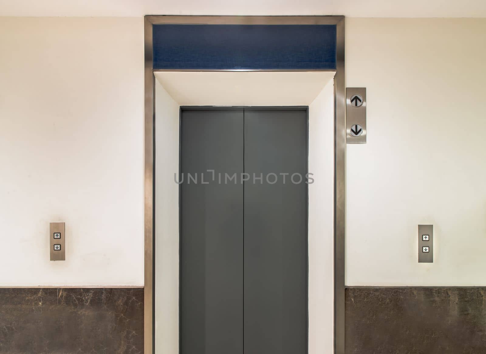 Elevator chrome metal with closed door in condominium. Lift transportation floor to floors with push switch for up and down. Selective focus.
