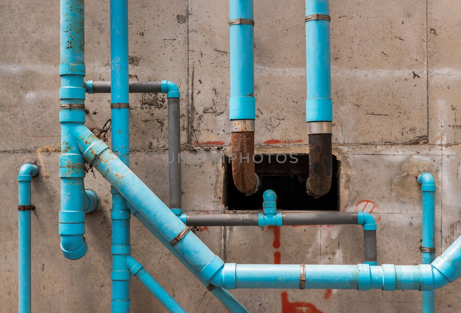 Blue water plastic pipes on the concrete wall in the condominium building. Installation of drainage pipes in the building. Sanitary system of a condominium. Water piping system install with the concrete ceiling. Texture pattern abstract background. Selective focus.