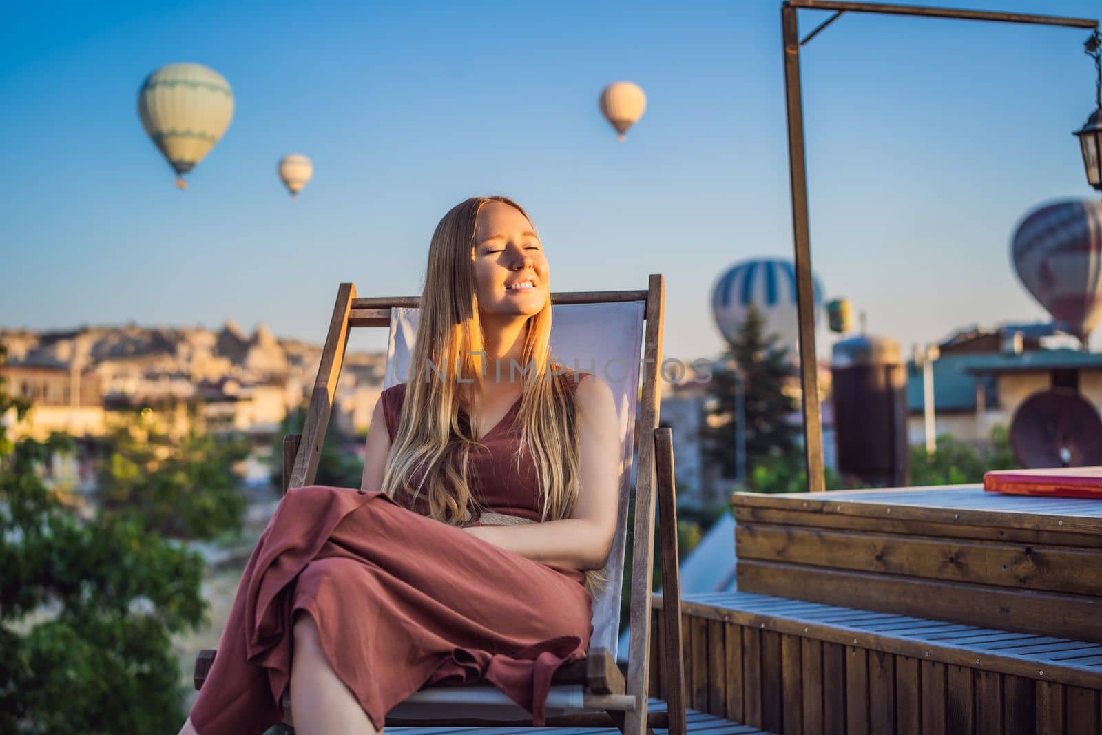 Tourist woman looking at hot air balloons in Cappadocia, Turkey. Happy Travel in Turkey concept. Woman on a mountain top enjoying wonderful view.