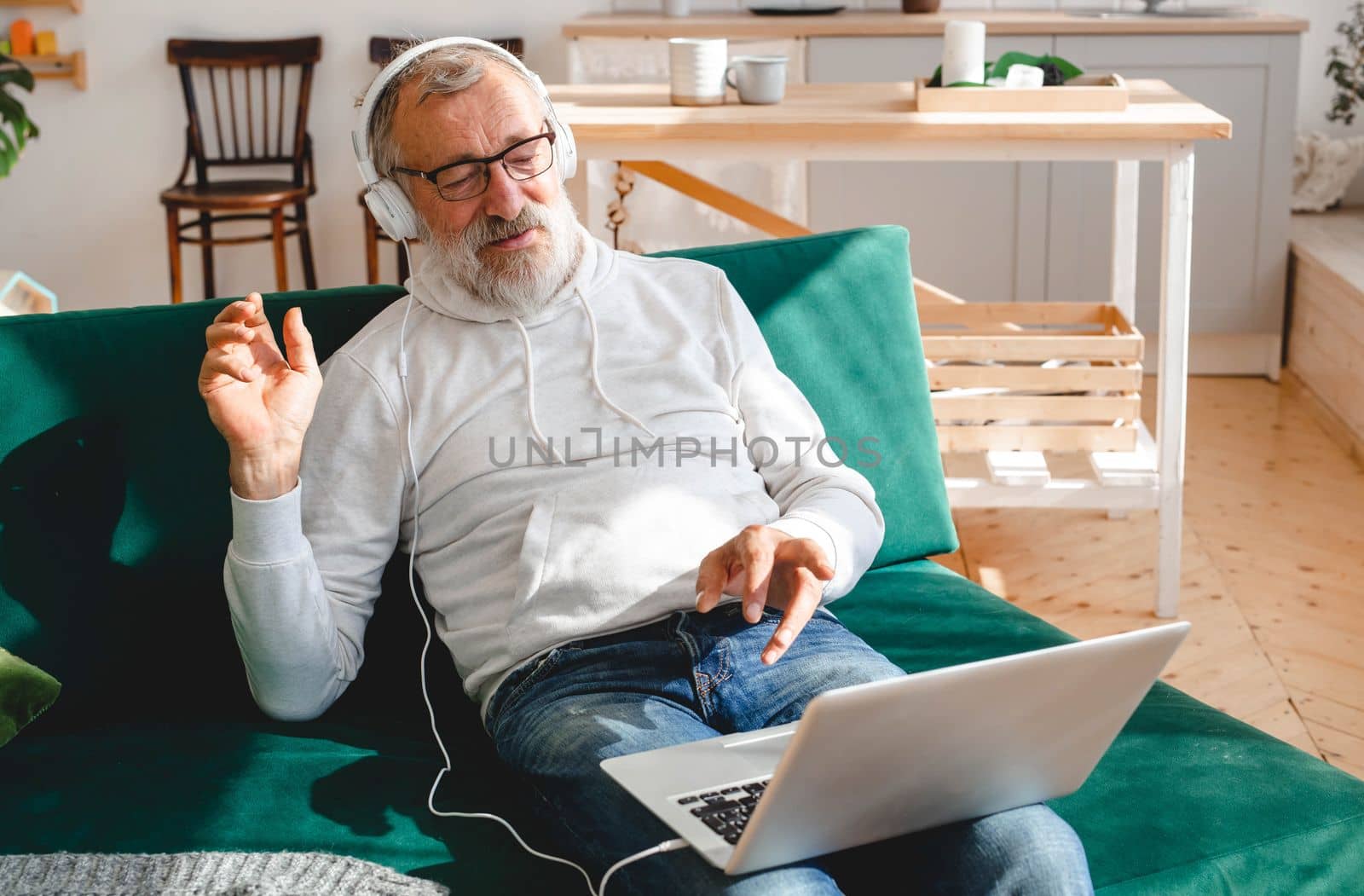 Elderly man making video call on laptop in room waving to screen and chatting with children - modern technologies communication and internet by Satura86