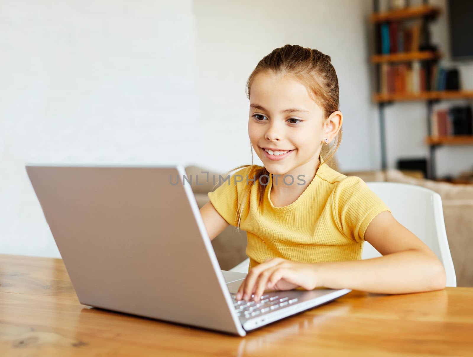 Portrait of a little girl having fun using laptop or doing homework with laptop at home