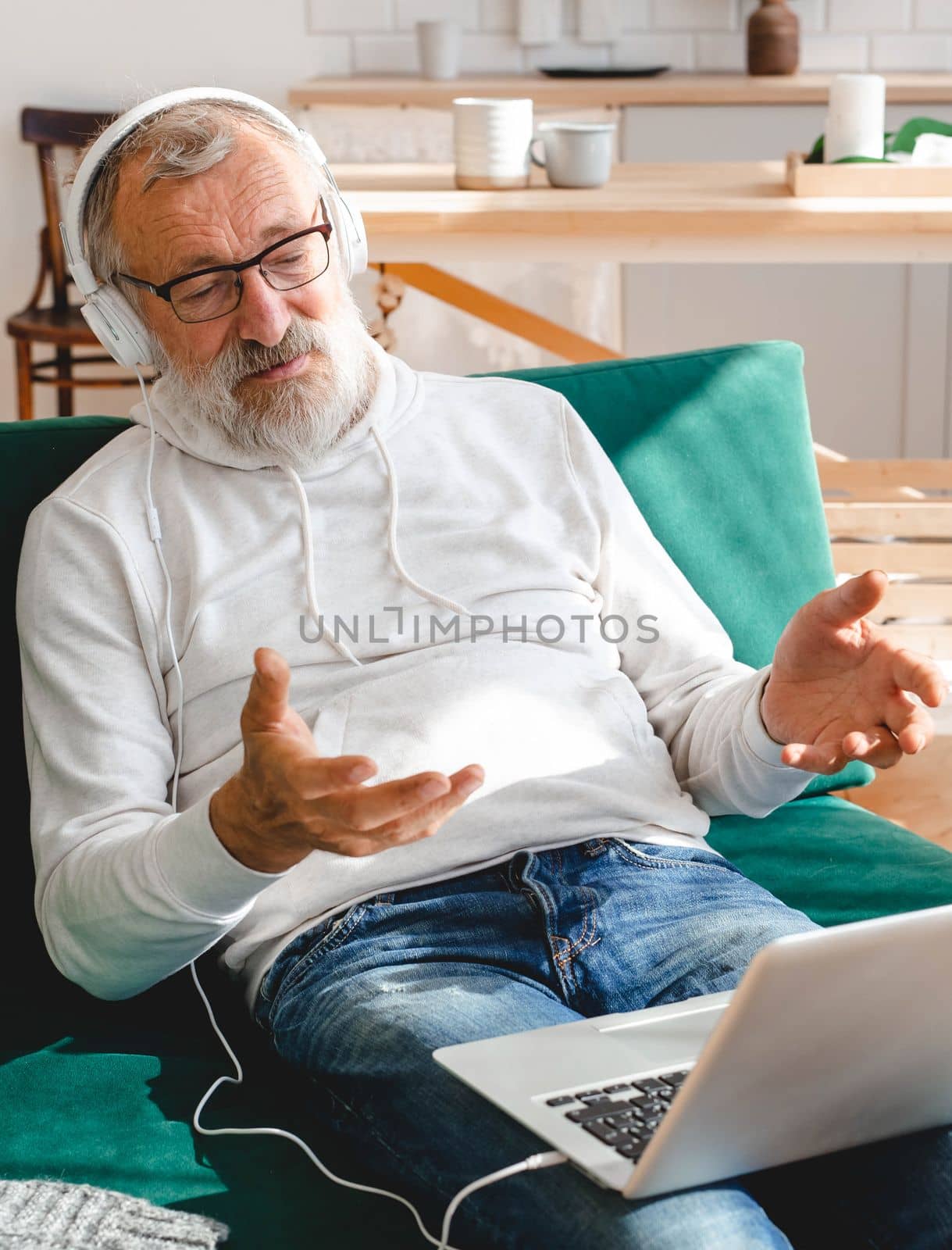 Elderly man making video call on laptop in room waving to screen and chatting with children - modern technologies communication and internet by Satura86