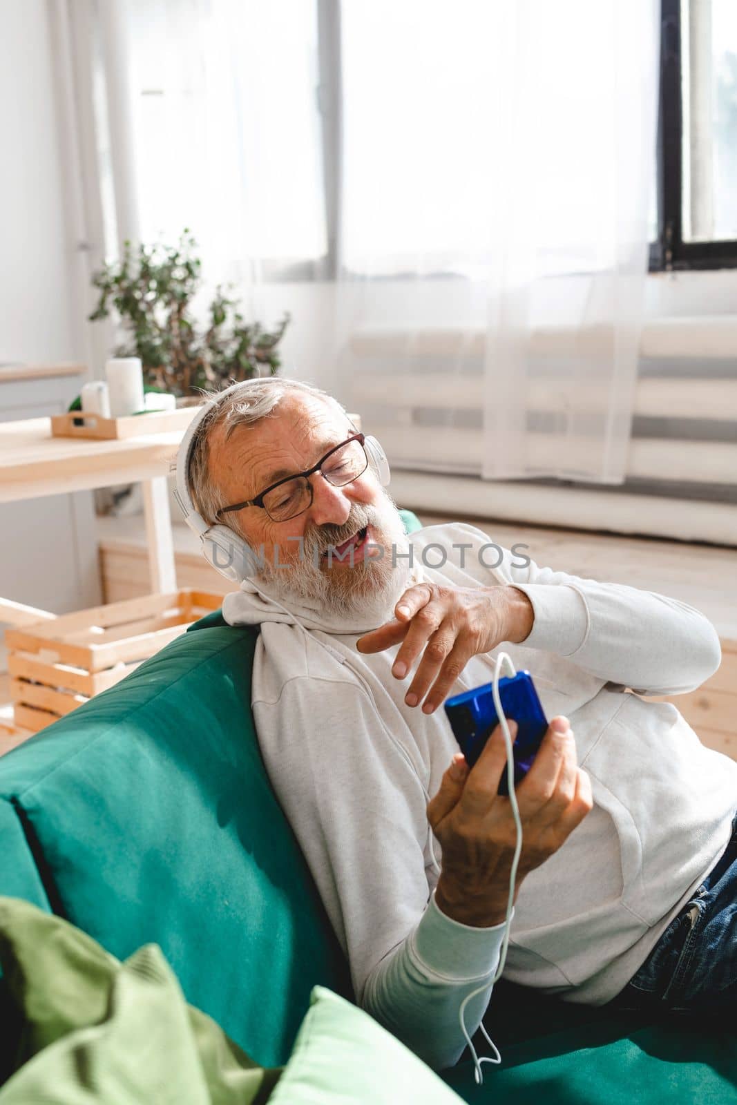 Elderly man making video call on smartphone in room waving to screen and chatting with children - modern technologies communication and internet by Satura86