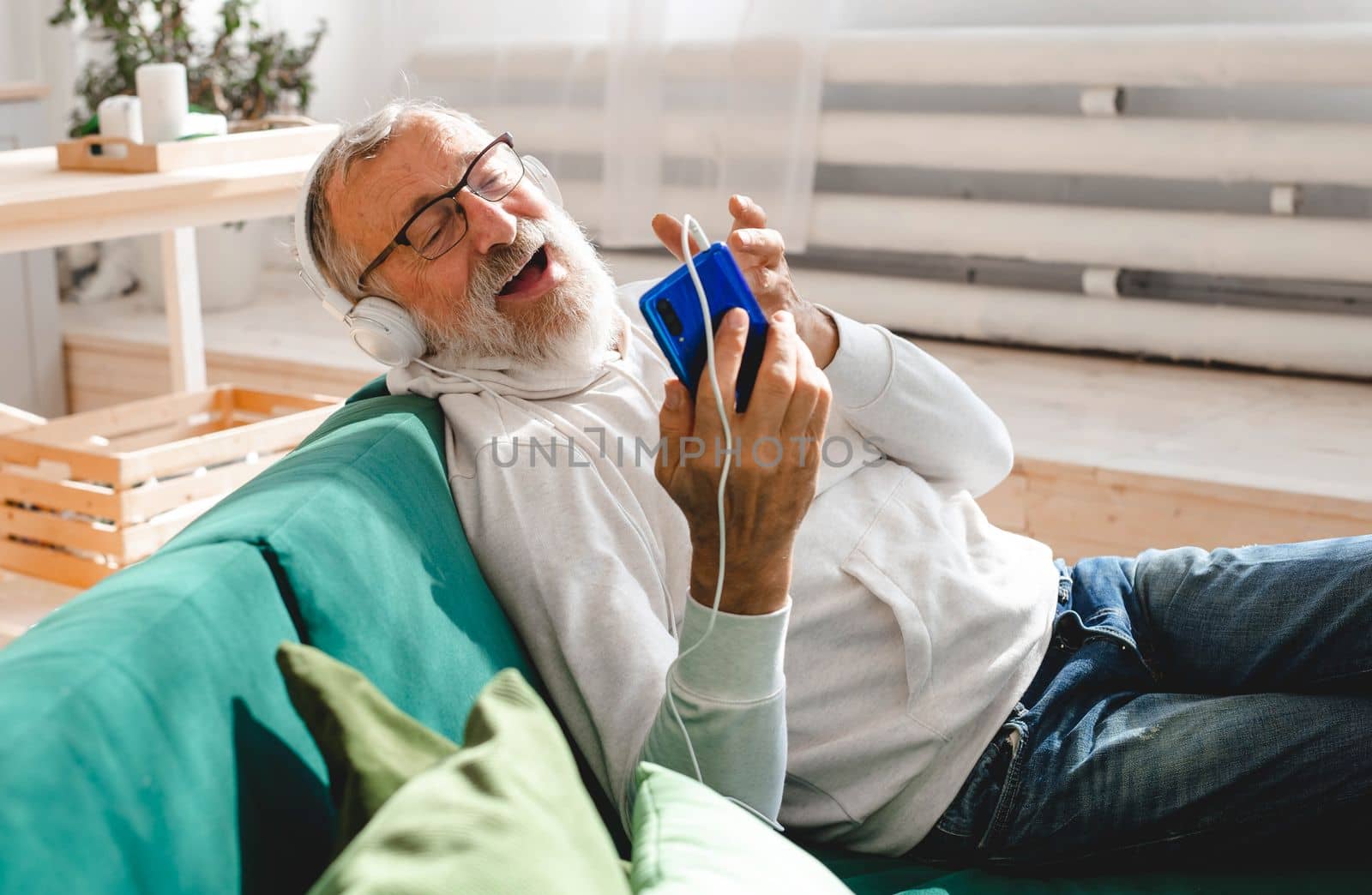 Elderly man making video call on laptop in room waving to screen and chatting with children - modern technologies communication internet