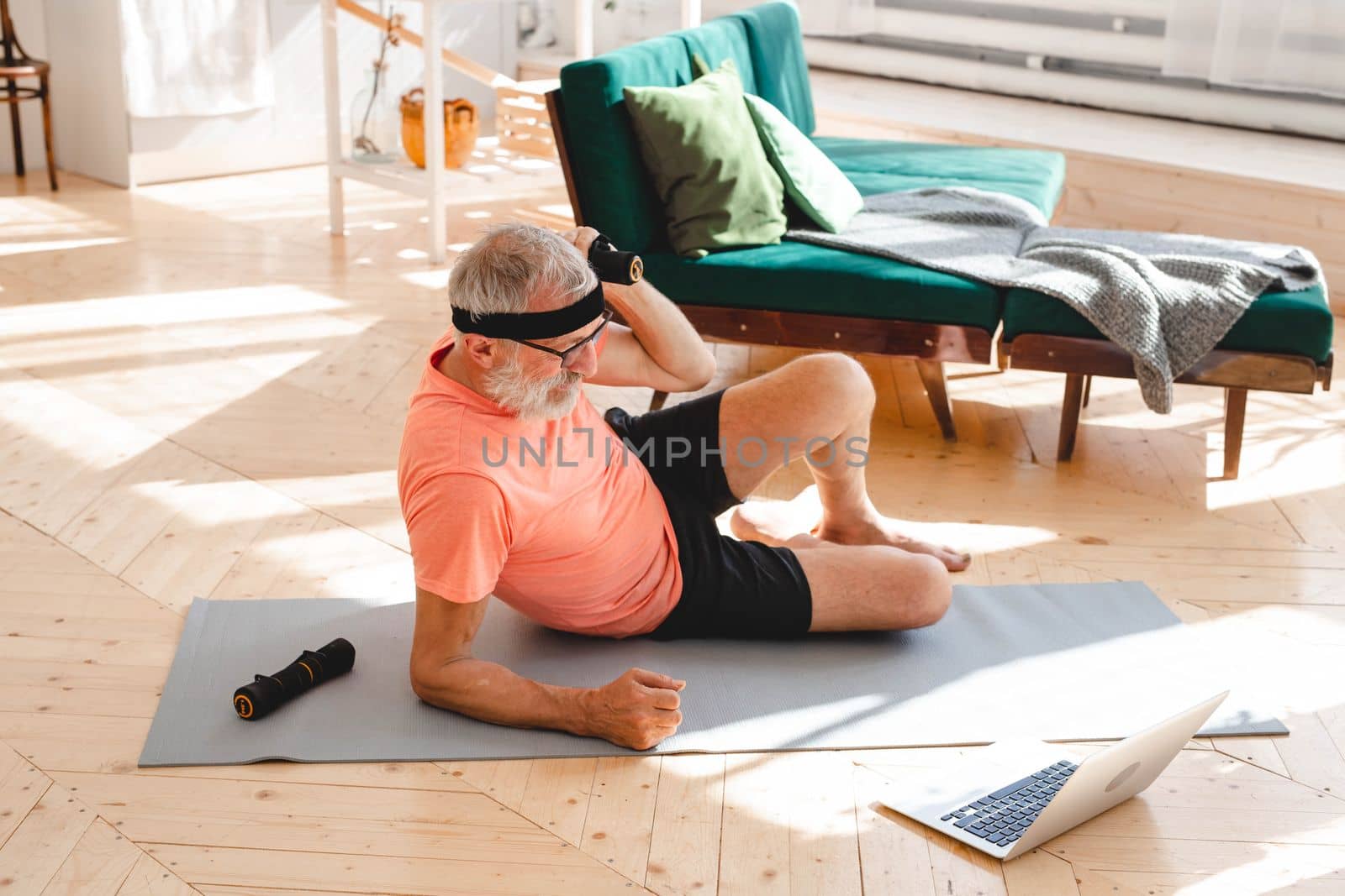 Elderly aged male exercising with dumbbells during online training. Old person man pensioner healthy training healthcare sport at home exercising fitness activity elderly age