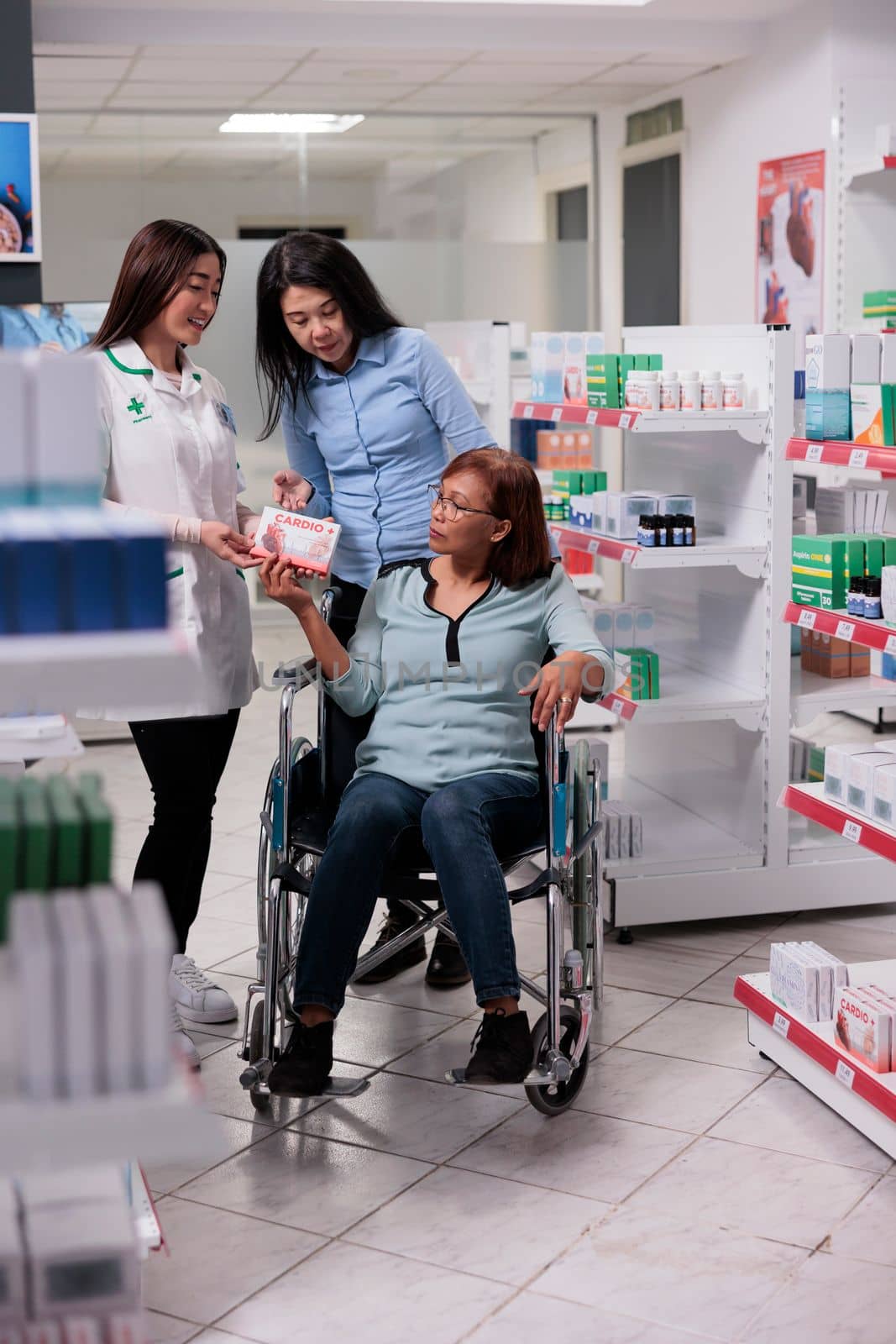 Medical assistant helping client with physical disability, talking to social worker and wheelchair user about medicaments and boxes of pills. Giving treatment with drugs and vitamins.