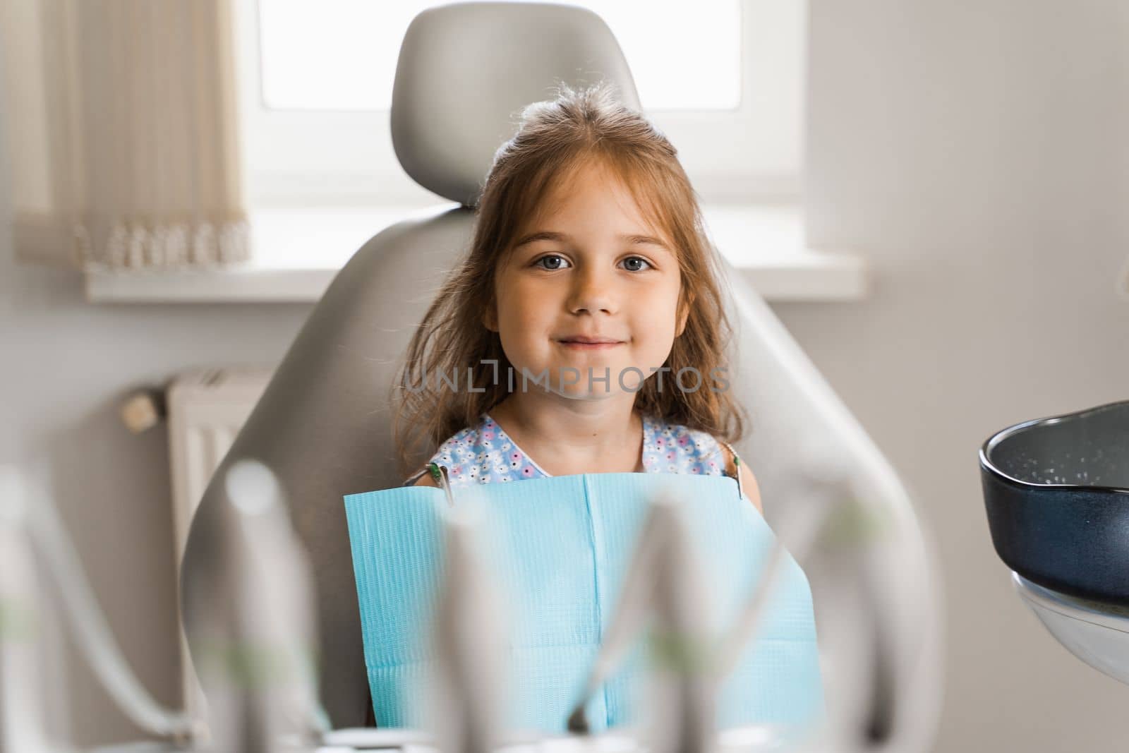 Happy child patient of dentistry. Teeth treatment. Attractive kid girl sitting in dental office and smiling. Child at dentist visiting