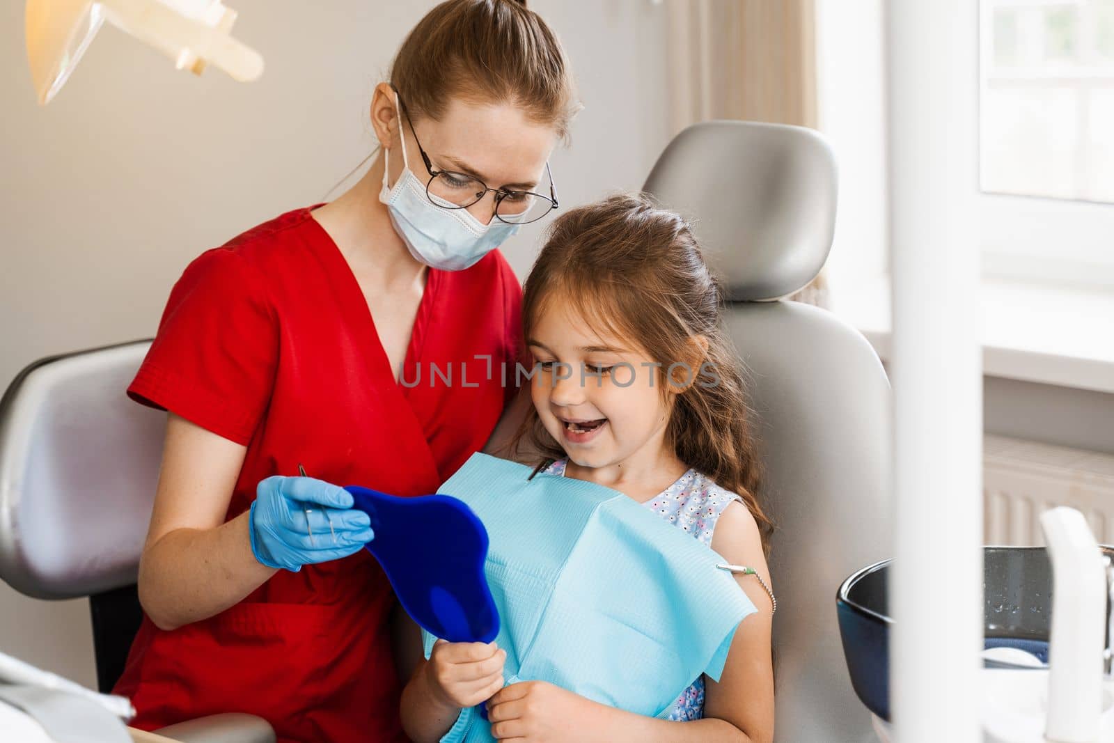 Consultation with child dentist at dentistry. Teeth treatment. Child looking in the mirror at the dentist. Happy child patient of dentistry