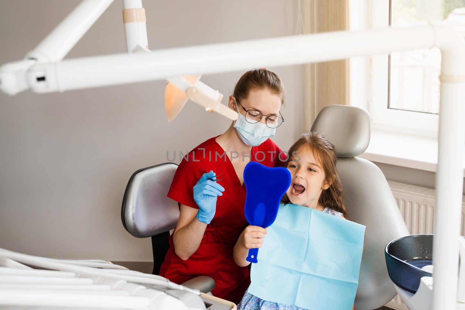Consultation with child dentist at dentistry. Teeth treatment. Child looking in the mirror at the dentist. Happy child patient of dentistry