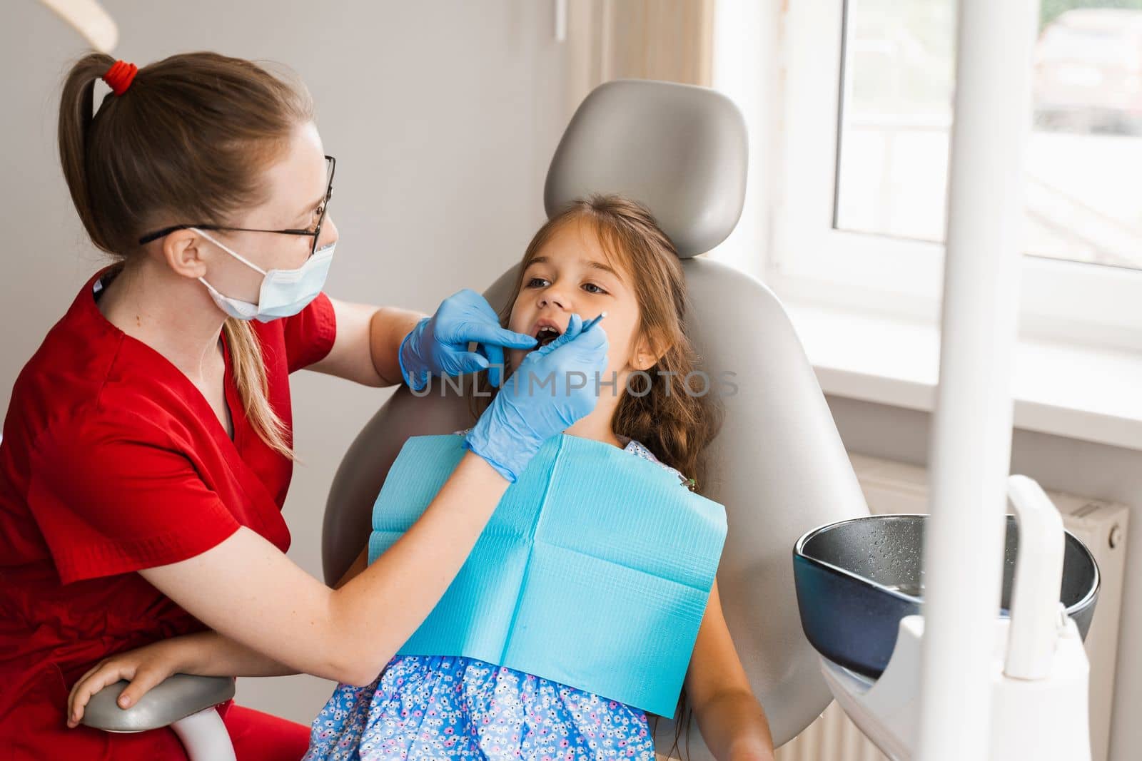 Pediatric dentist examines teeth of child girl for treatment of toothache. Pain in teeth in children. Consultation with pediatric dentist in dentistry