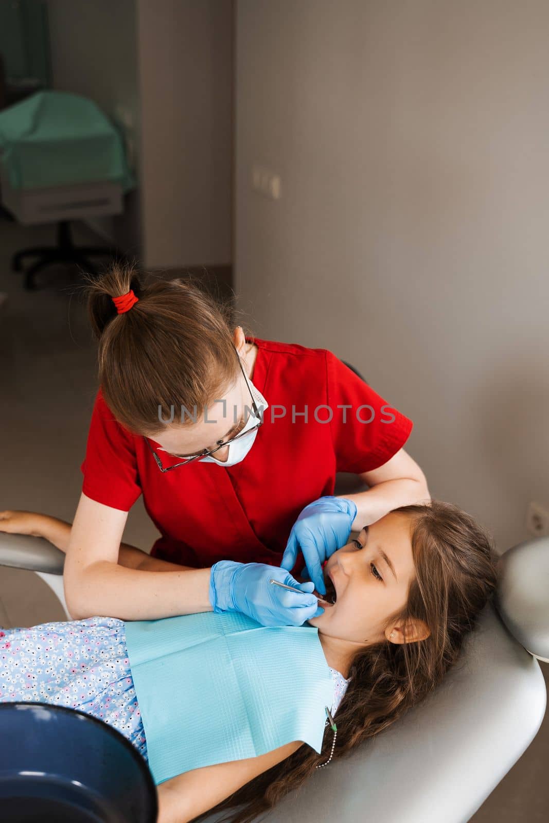 Consultation with child dentist at dentistry. Teeth treatment. Children dentist examines girl mouth and teeth and treats toothaches. Happy child patient of dentistry. by Rabizo