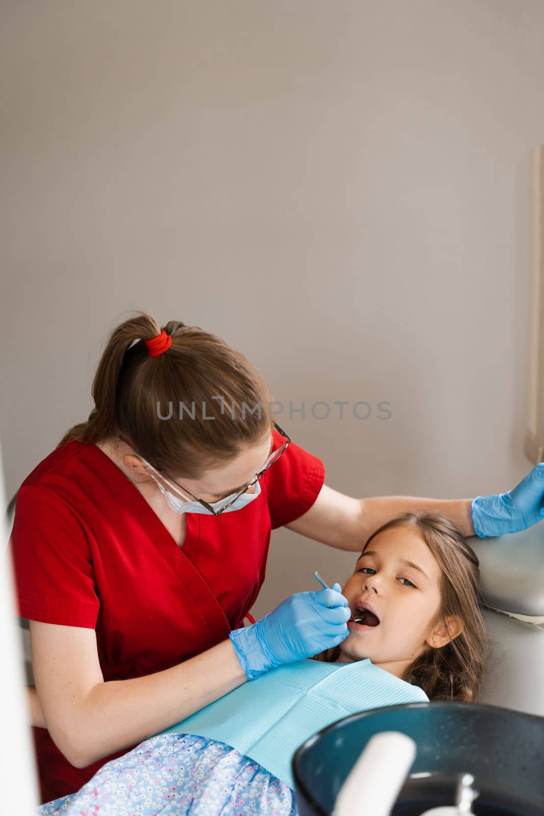 Consultation with child dentist at dentistry. Teeth treatment. Children dentist examines girl mouth and teeth and treats toothaches. Happy child patient of dentistry